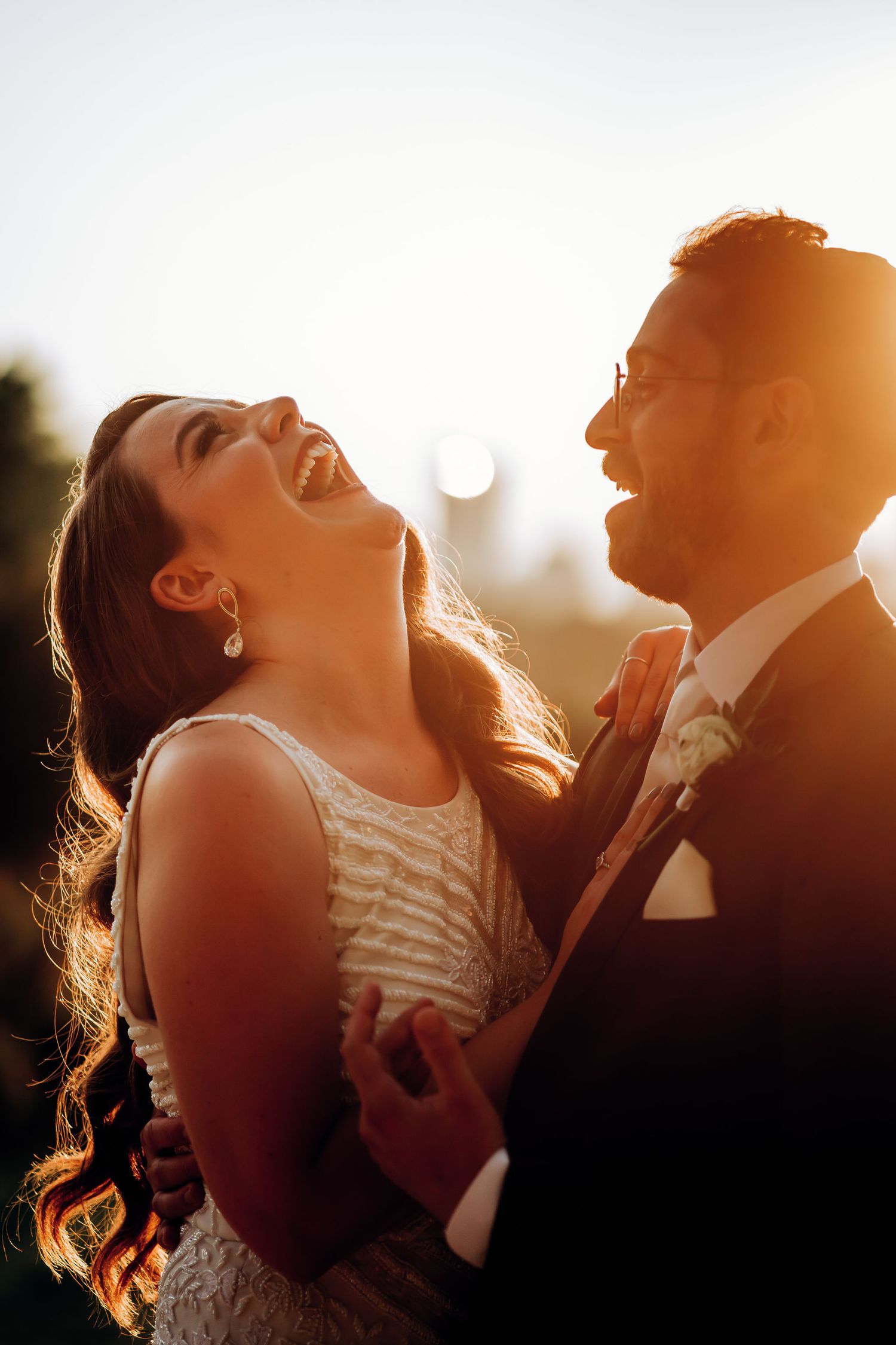 Candid moment of laughter between couple during golden hour wedding portrait session.