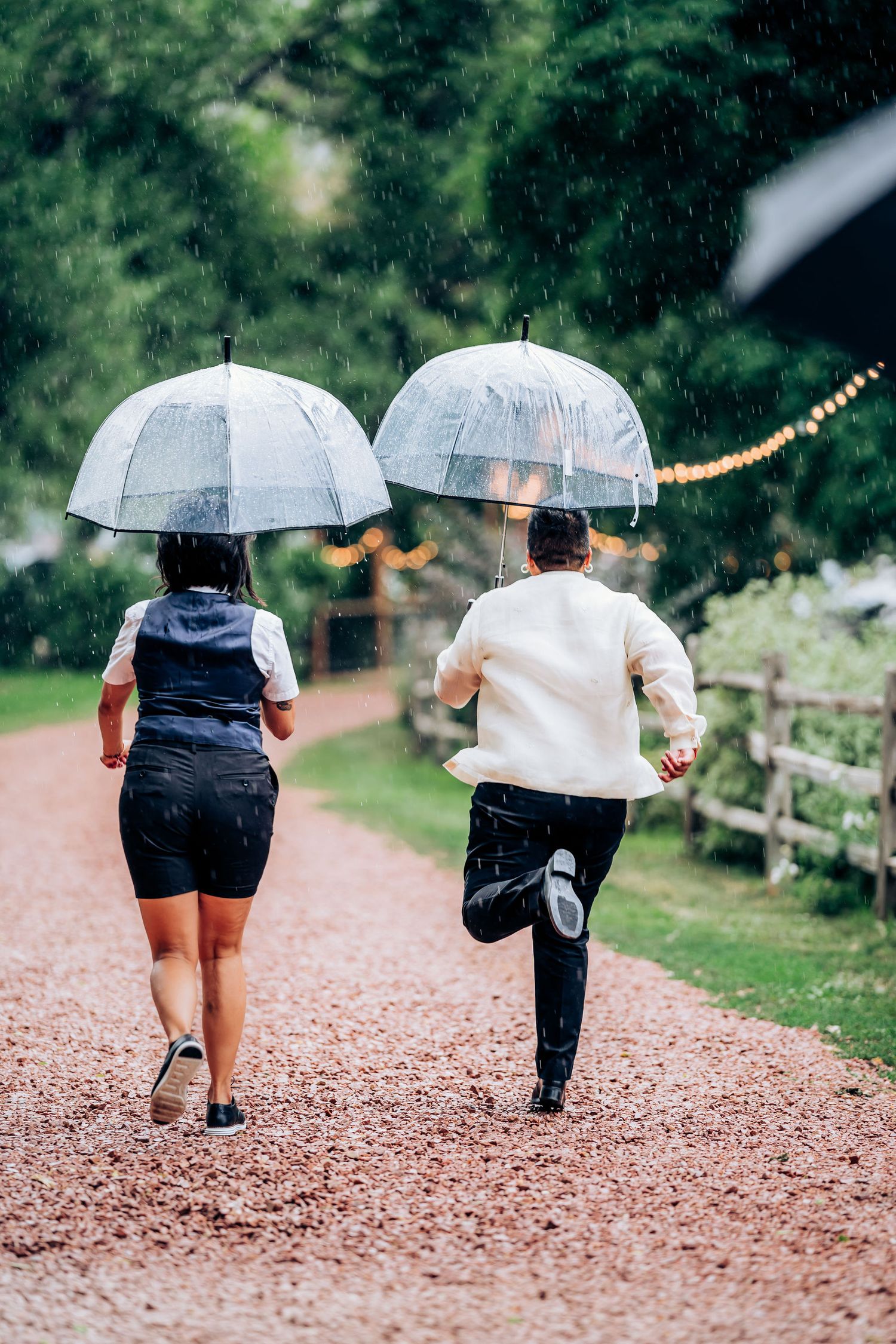 Two people walking with clear umbrellas on a rainy path.