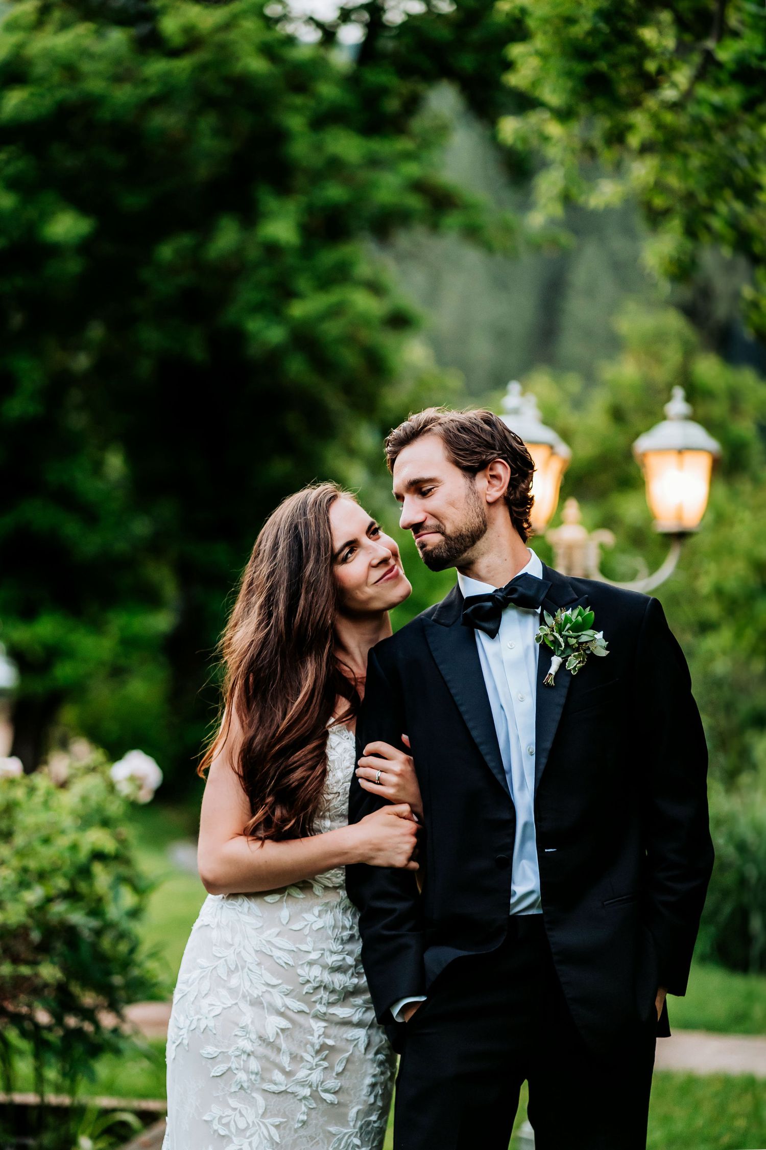 A romantic moment between newlyweds in an elegant garden setting with glowing lanterns.
