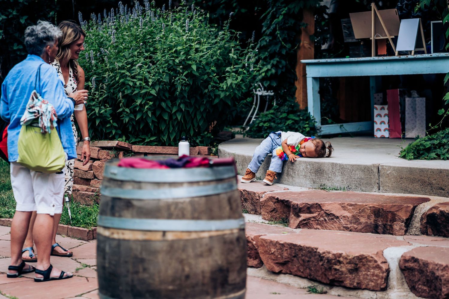 People explore outdoor seating area with wooden barrel and stone steps.