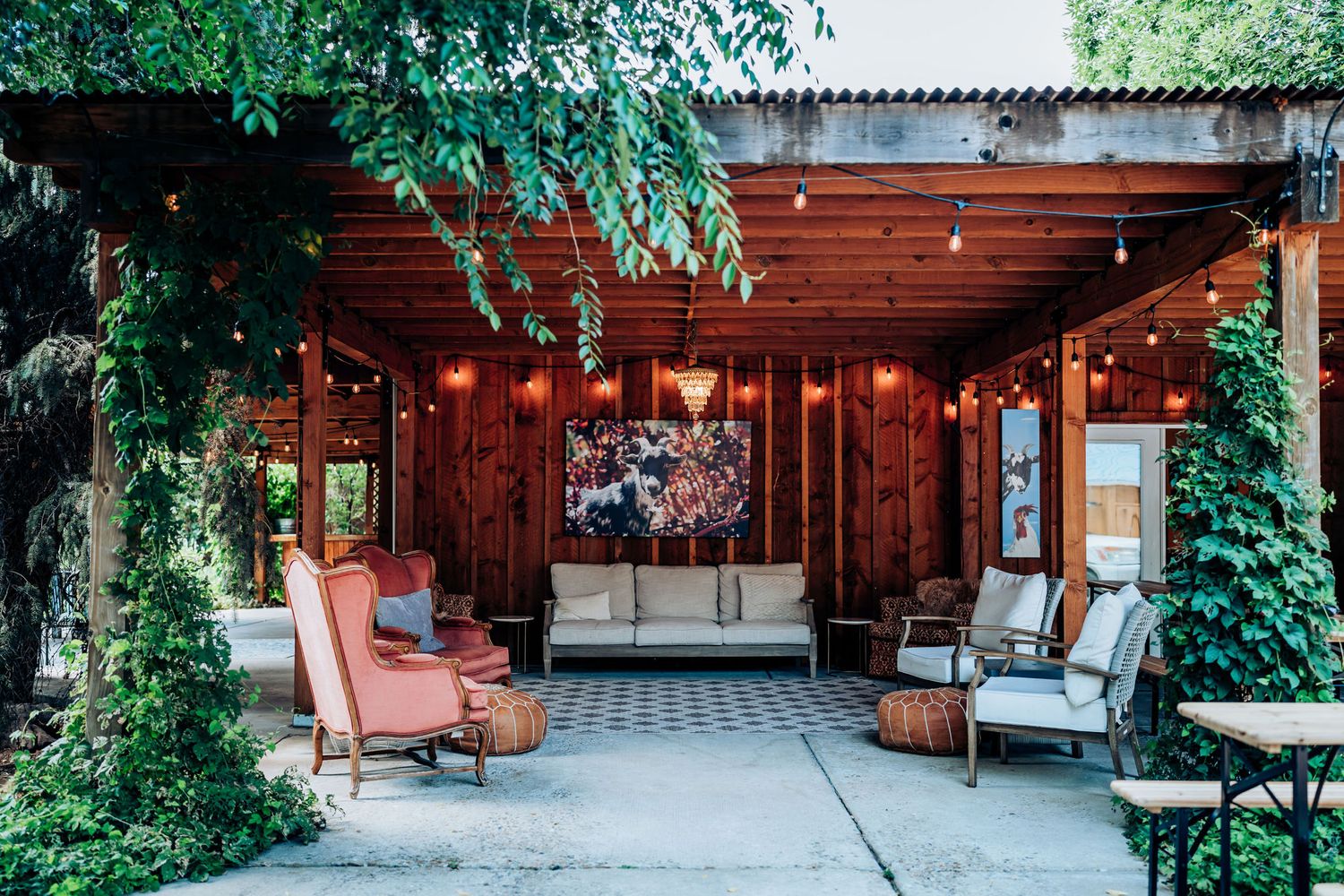 Cozy outdoor patio area with string lights and comfortable seating against wooden walls.