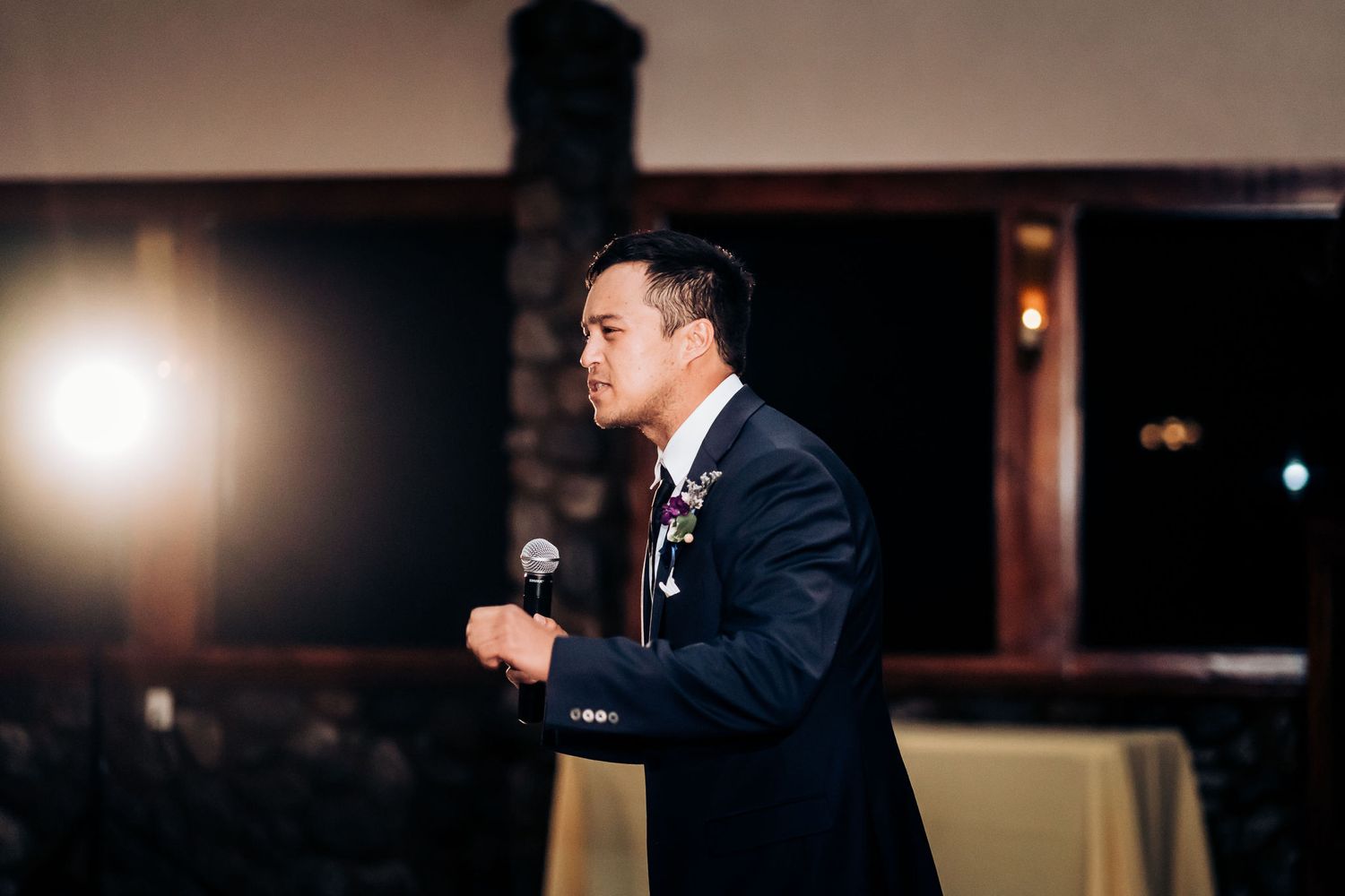 Speaker delivers a speech at an evening event using a microphone.