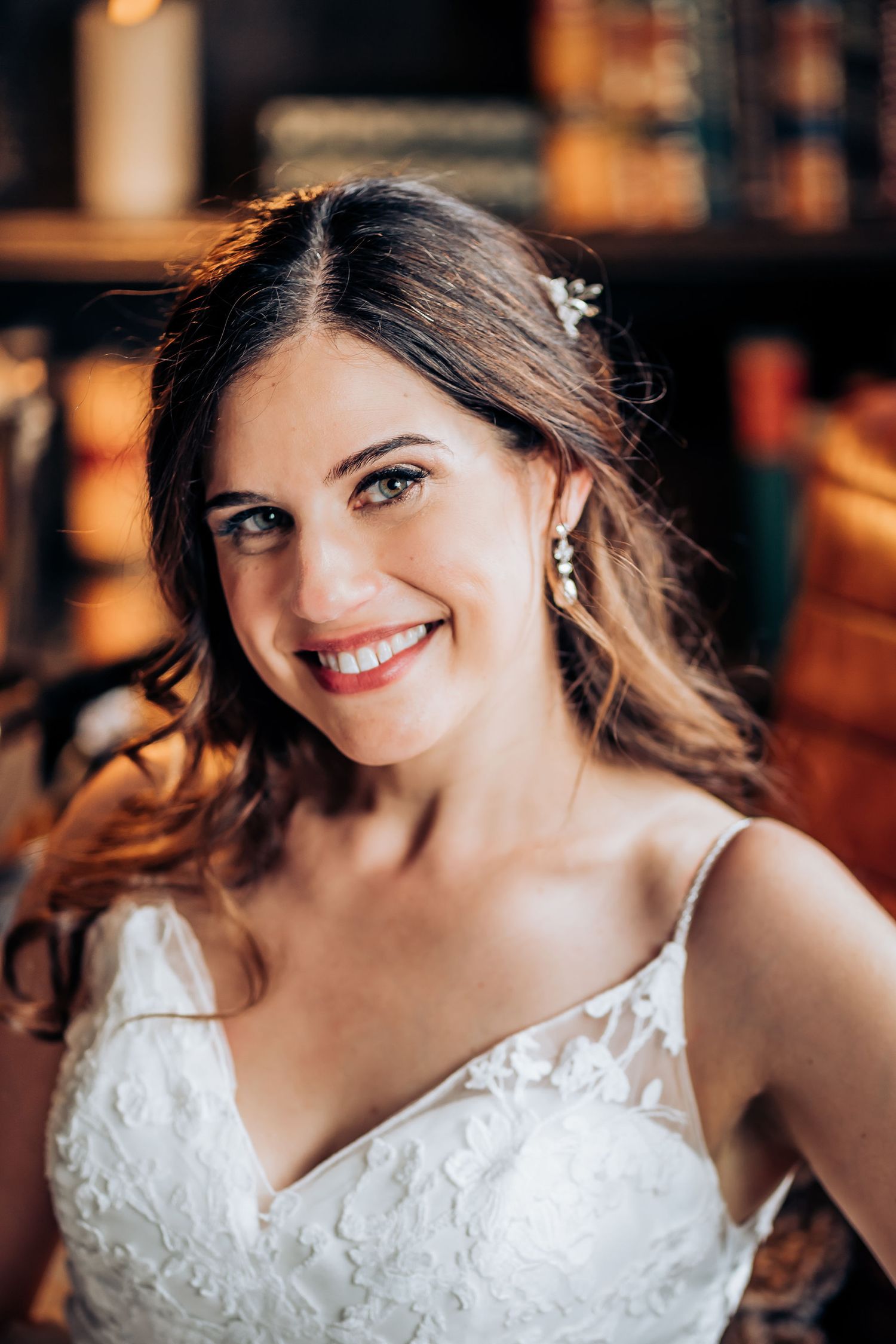 Close-up portrait in warm lighting showing wedding dress details.