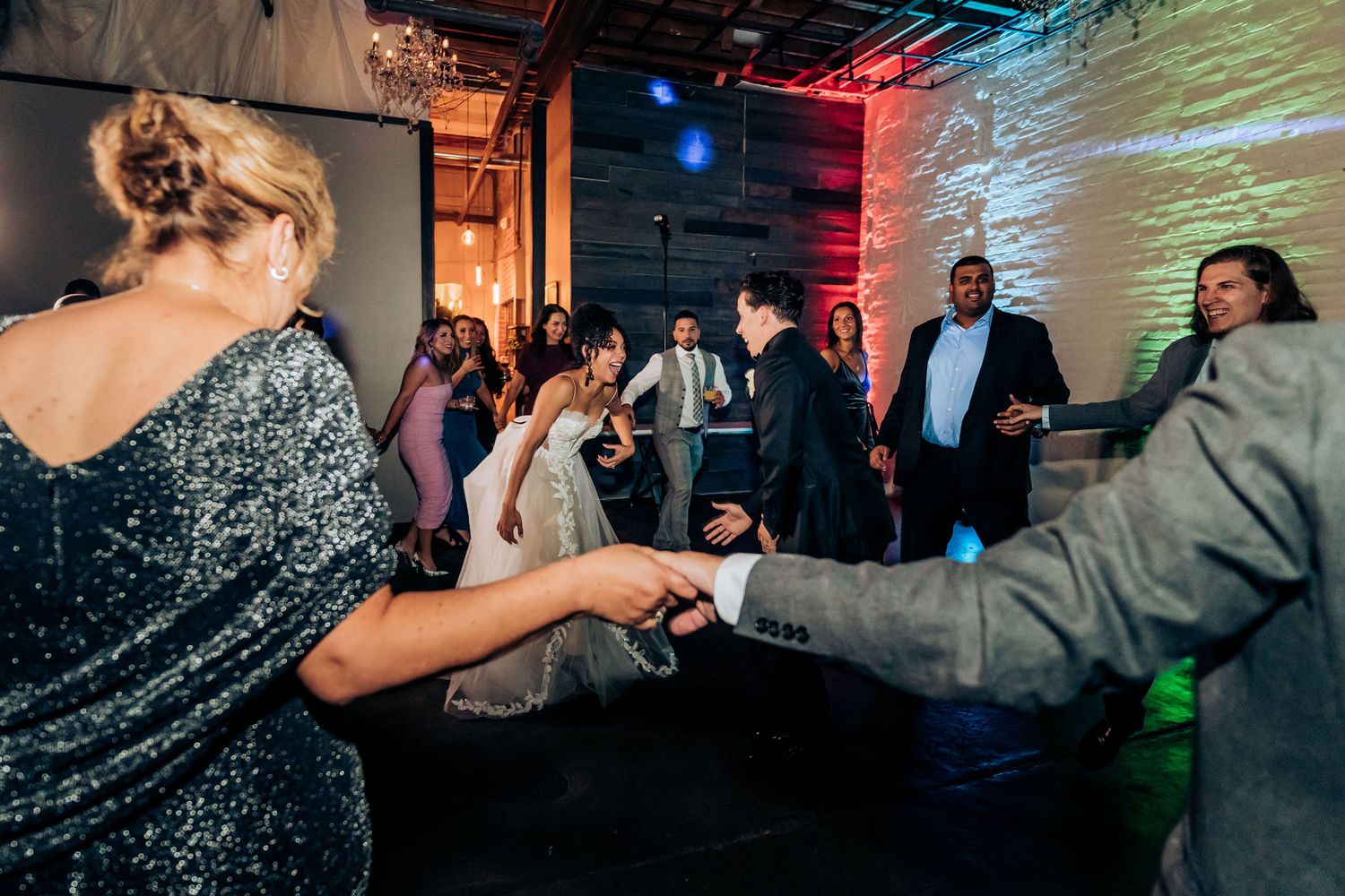 Wedding guests perform energetic dance moves on the reception dance floor.
