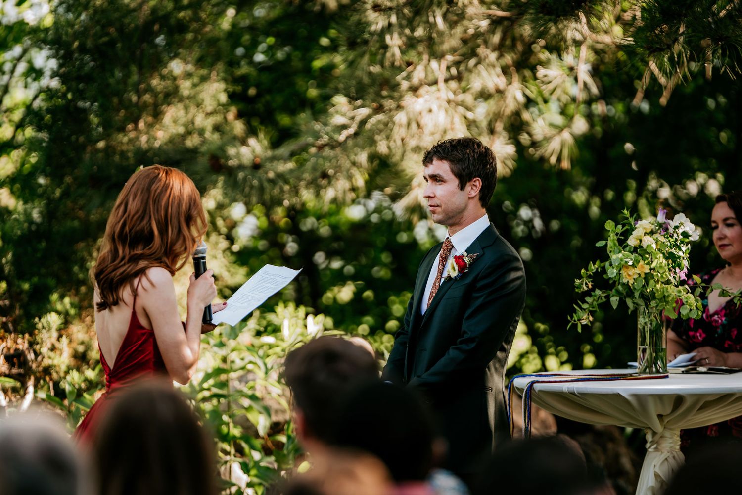 Emotional moment during outdoor wedding vows with natural garden backdrop.