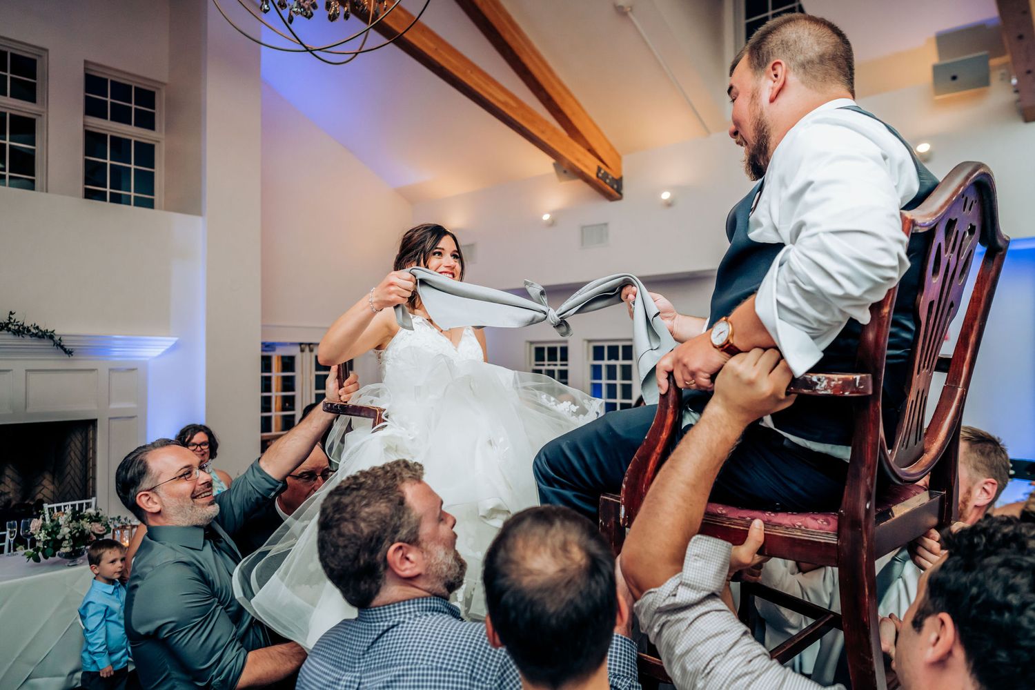 Wedding guests participate in traditional chair lifting dance celebration at reception.
