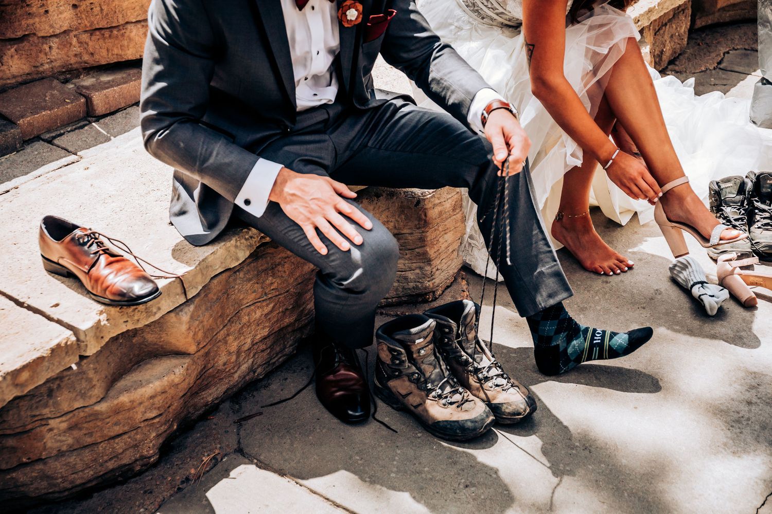 Wedding couple sitting on rustic wooden steps showing off their hiking boots and dress shoes.