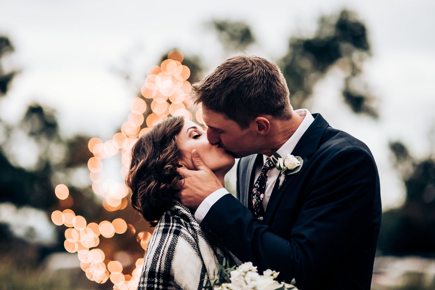 Romantic wedding photo with bokeh lights creating a dreamy atmosphere in the background.