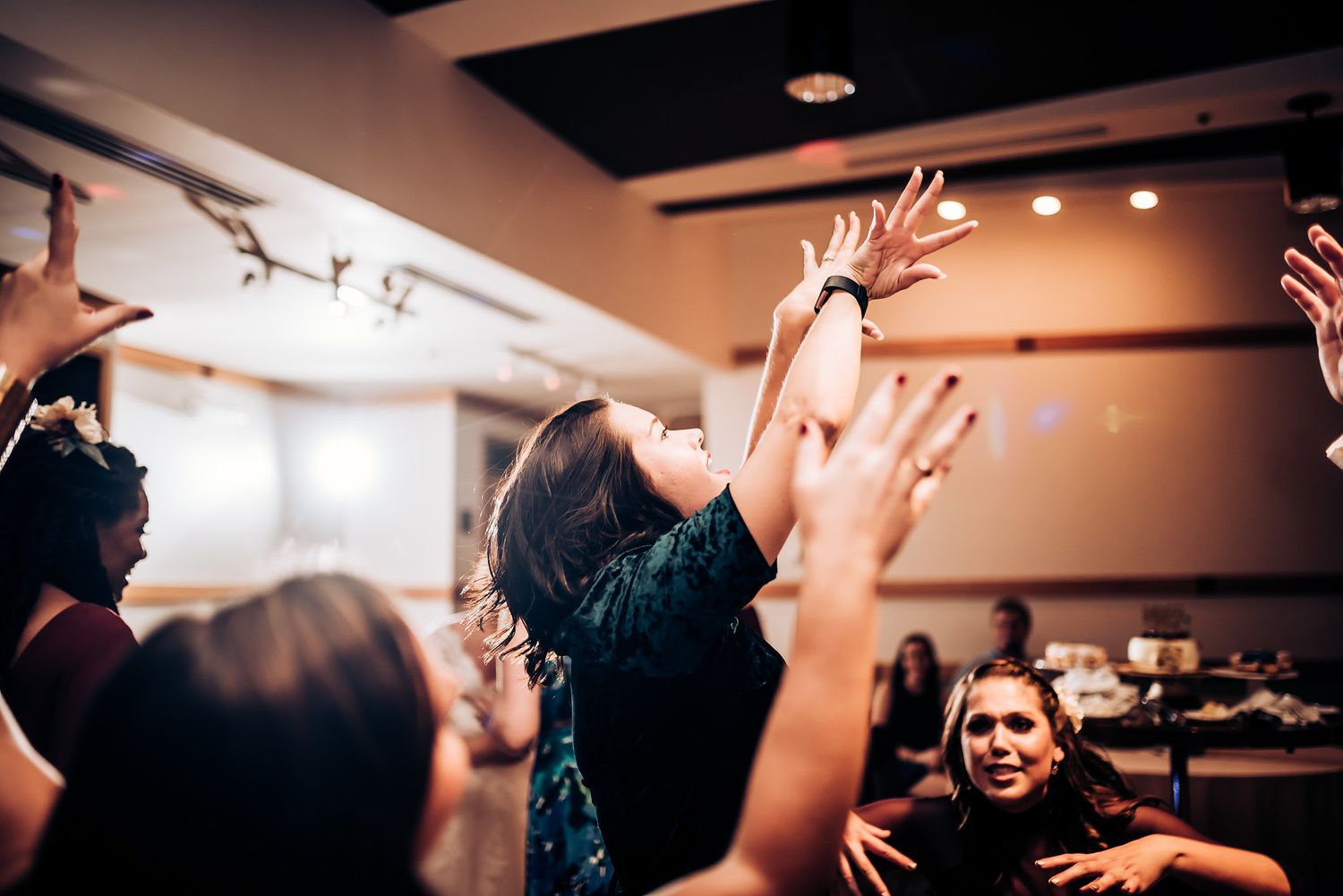 Guests raise their hands in celebration during a lively indoor party event.