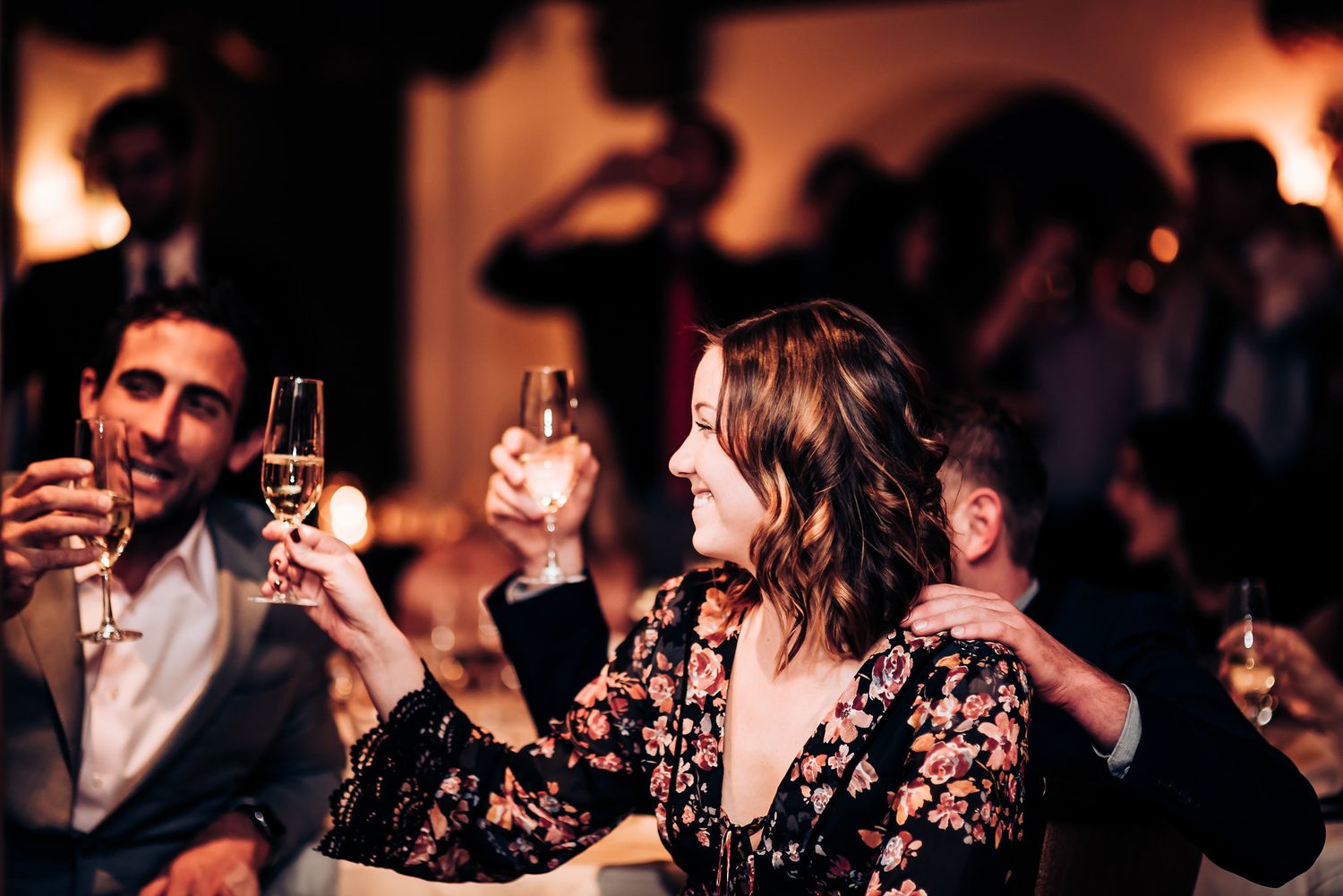 Wedding guests raise champagne glasses for a celebratory toast at an elegant evening reception.
