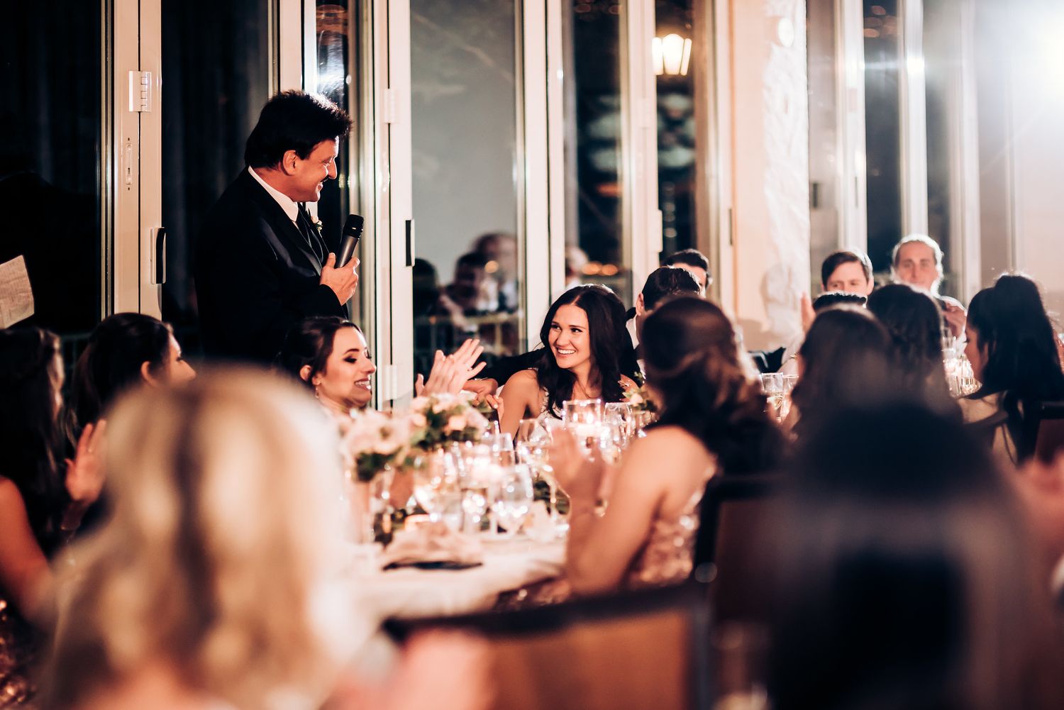 Wedding reception speech captivates guests seated at elegantly decorated dining tables.