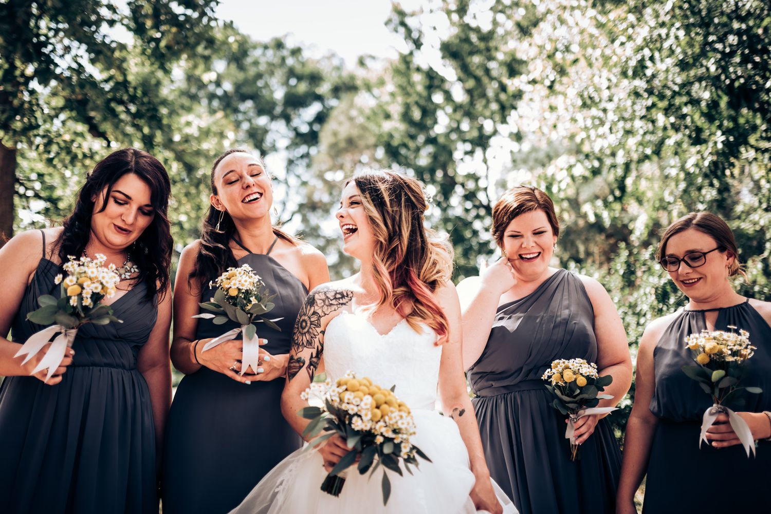 Bridal party shares joyful moment outdoors wearing navy dresses.