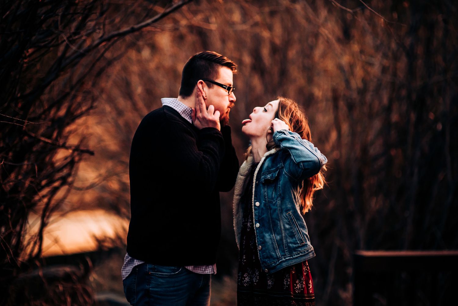 Couple laughing together against autumn sunset background.