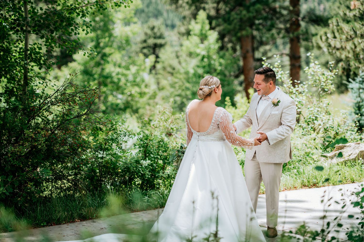 Newlyweds share an intimate moment on a path surrounded by mountain scenery.