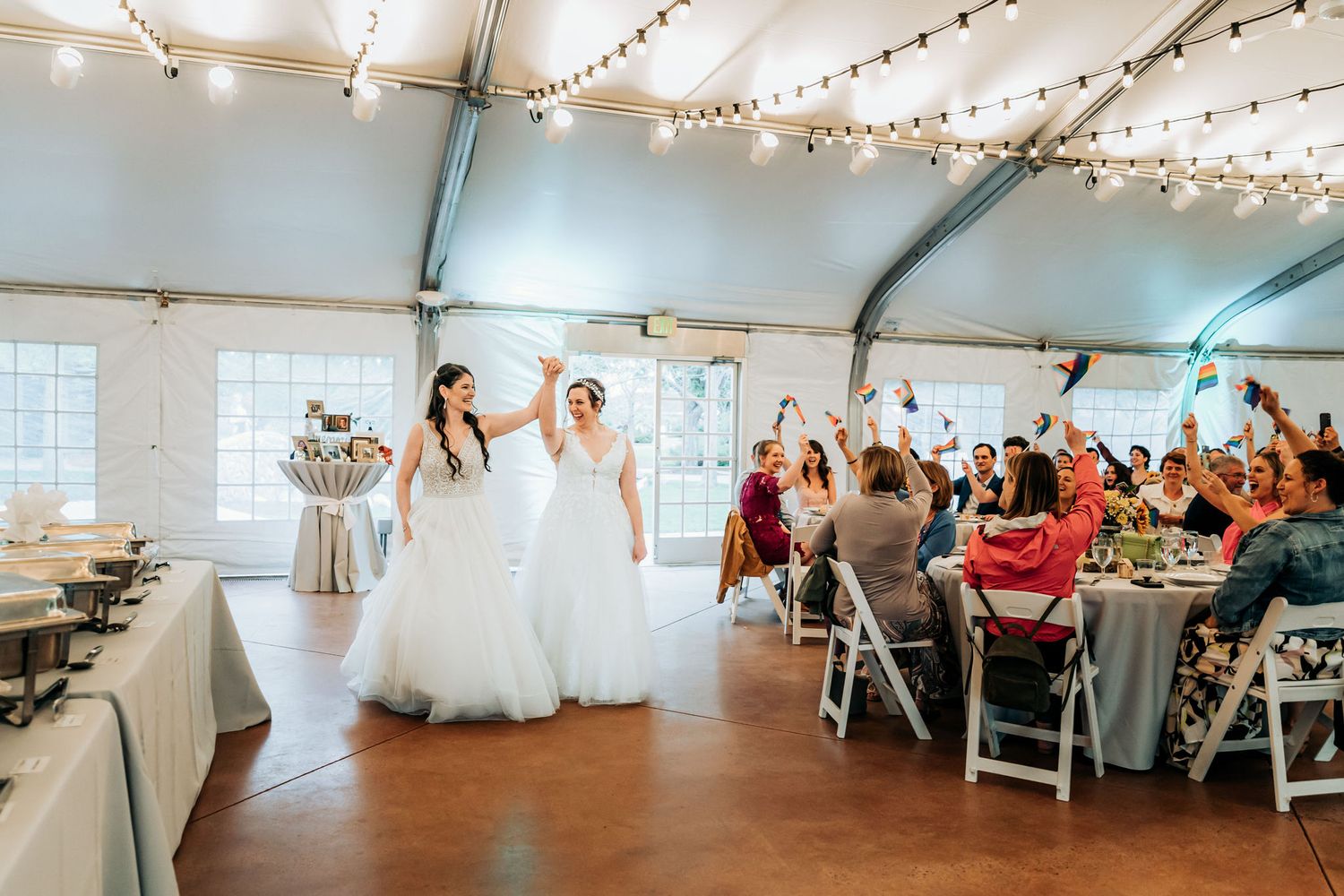 Wedding reception celebration in bright indoor venue with string lights and elegant white decor.