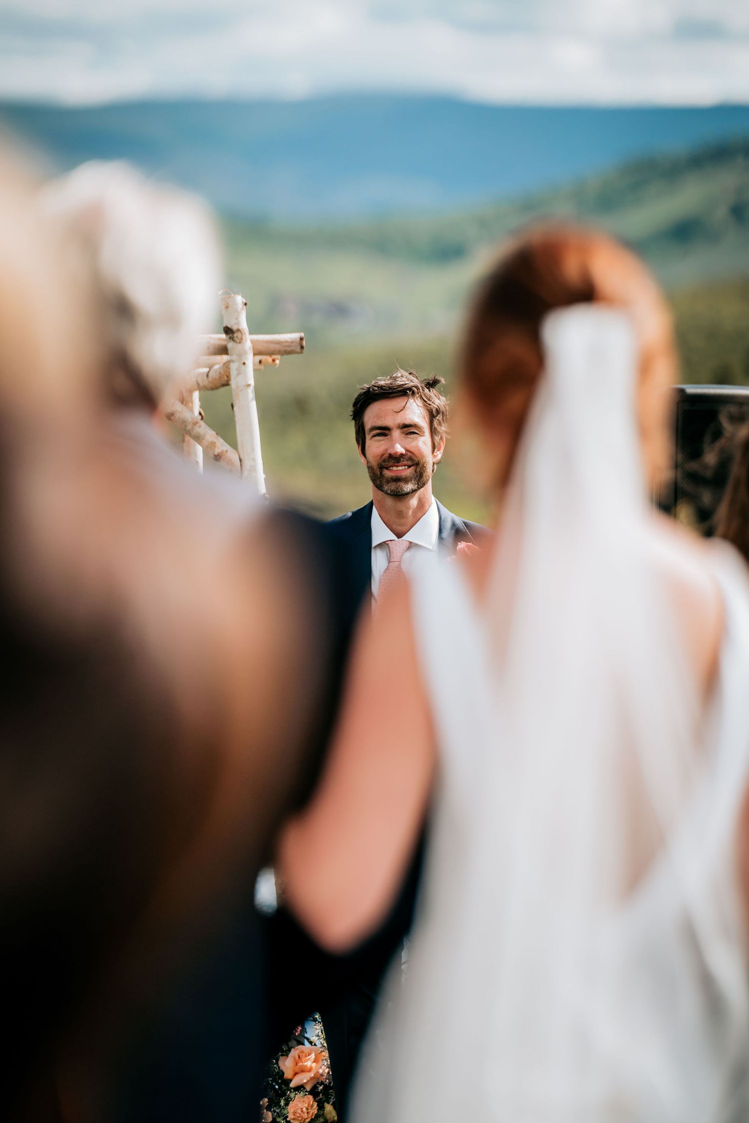 Wedding ceremony in mountain setting with cross and scenic views.