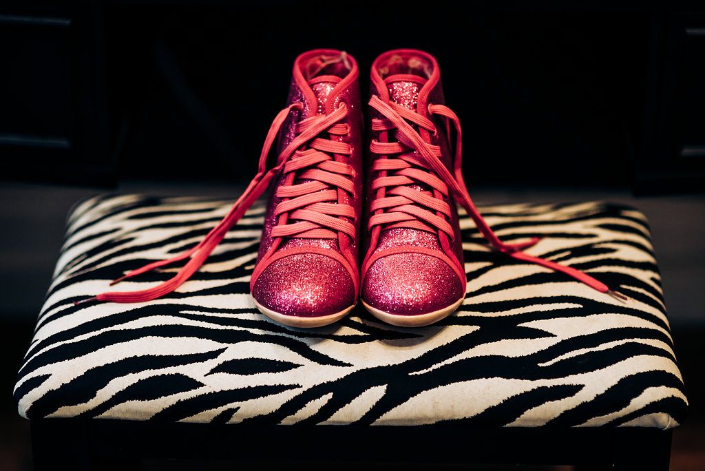 Sparkling red high-top sneakers placed on zebra print fabric.