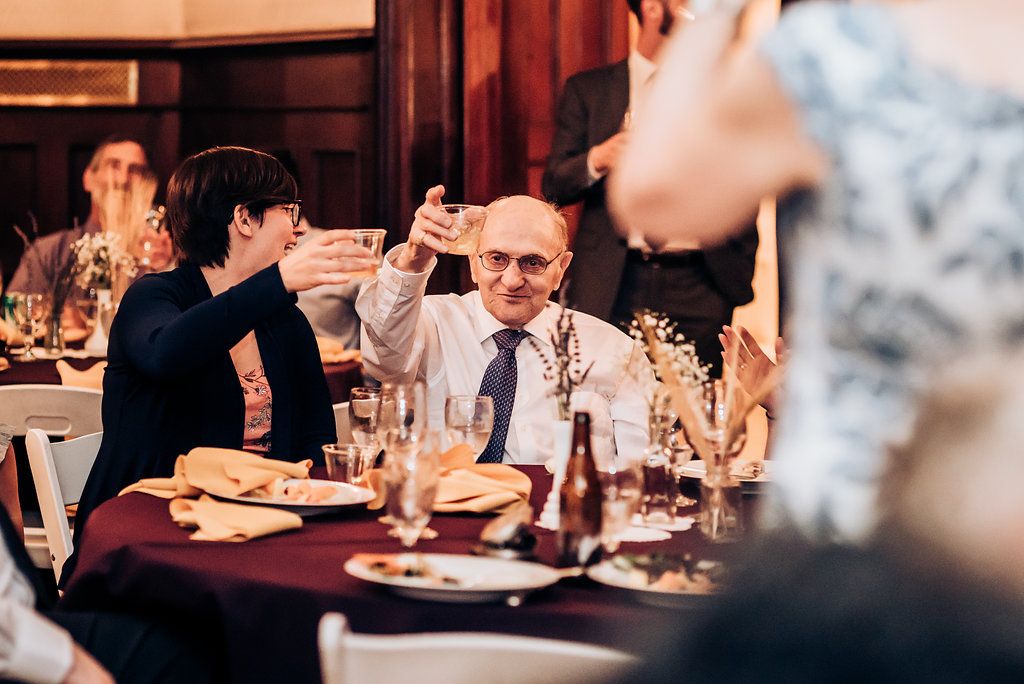 Guests engage in lively dinner conversation at an elegant restaurant with red tablecloths and ambient lighting.