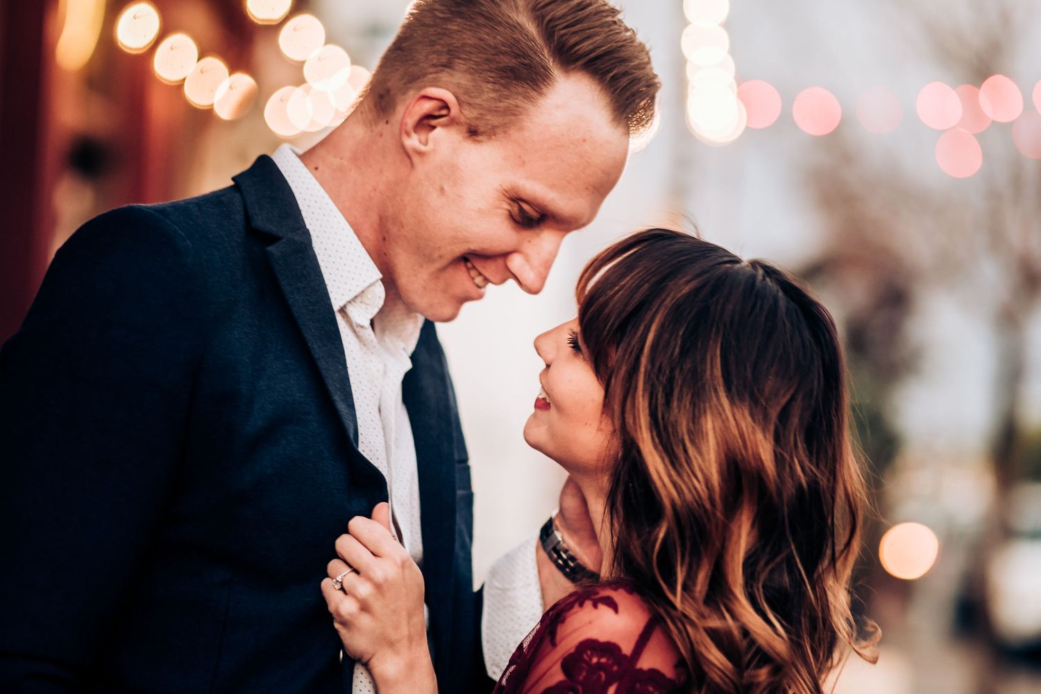 A romantic couple shares an intimate moment with soft bokeh lights in the background.