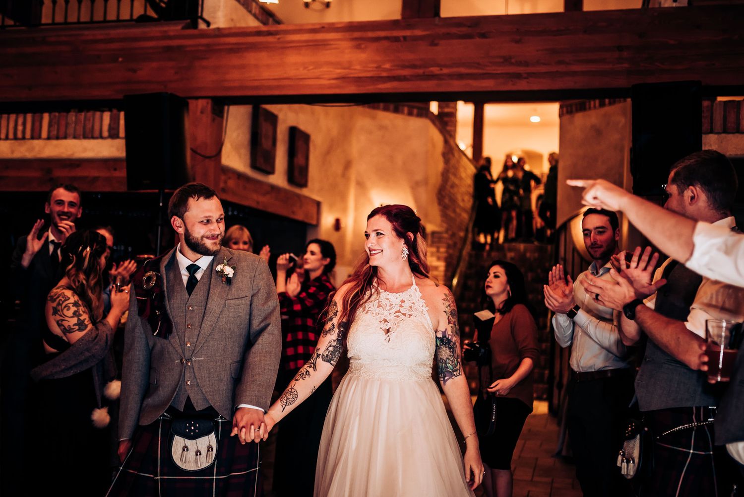Couple makes grand entrance at reception while guests cheer and applaud.