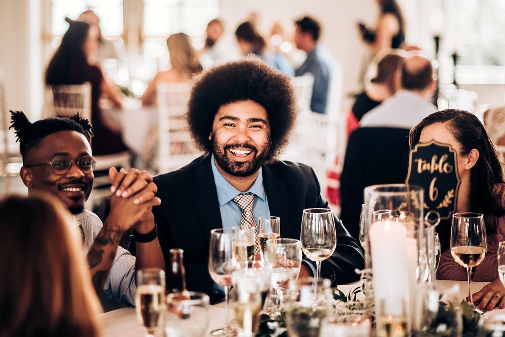 Wedding reception guests enjoying dinner conversation at a candlelit table.