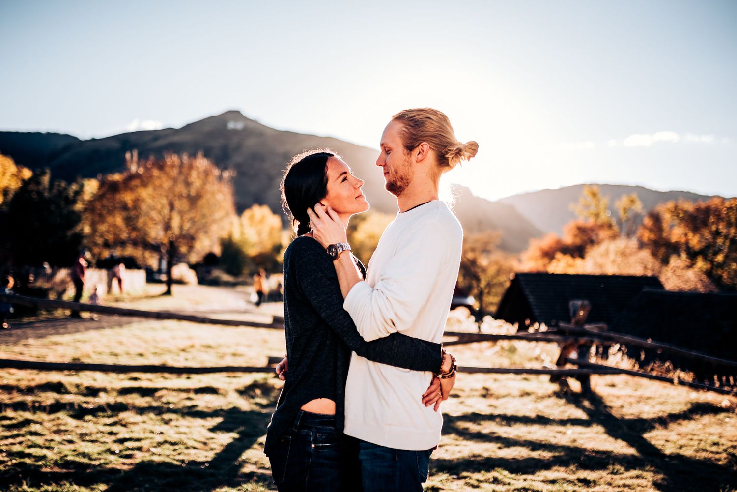 A loving couple shares an intimate moment outdoors with mountain scenery in the background.