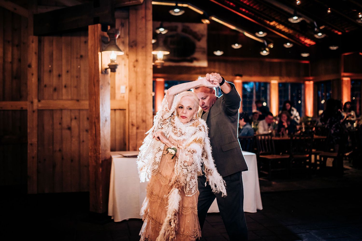Rustic barn reception with dancing couples in warm lighting.