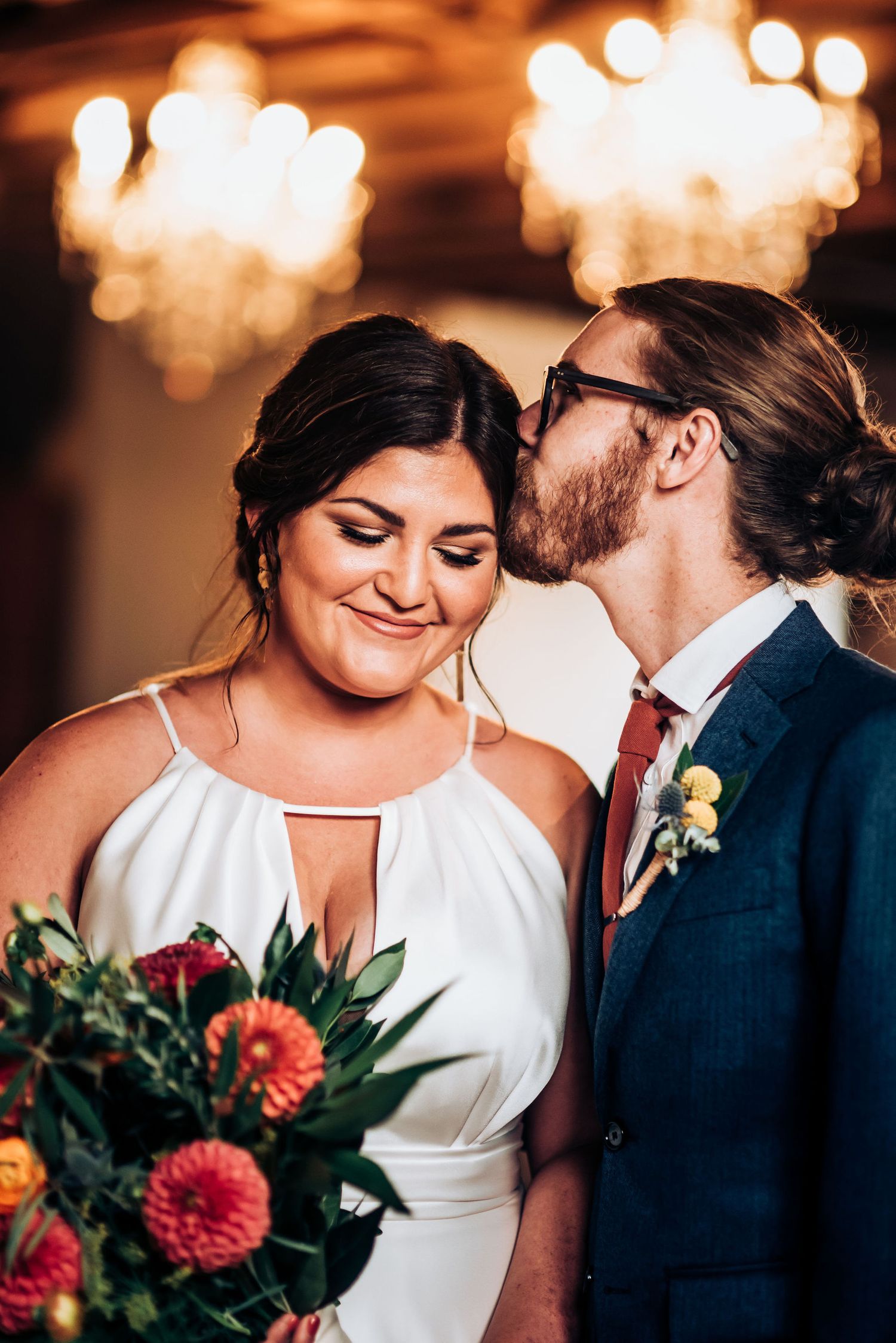 Intimate wedding couple moment with romantic lighting and coral floral bouquet.