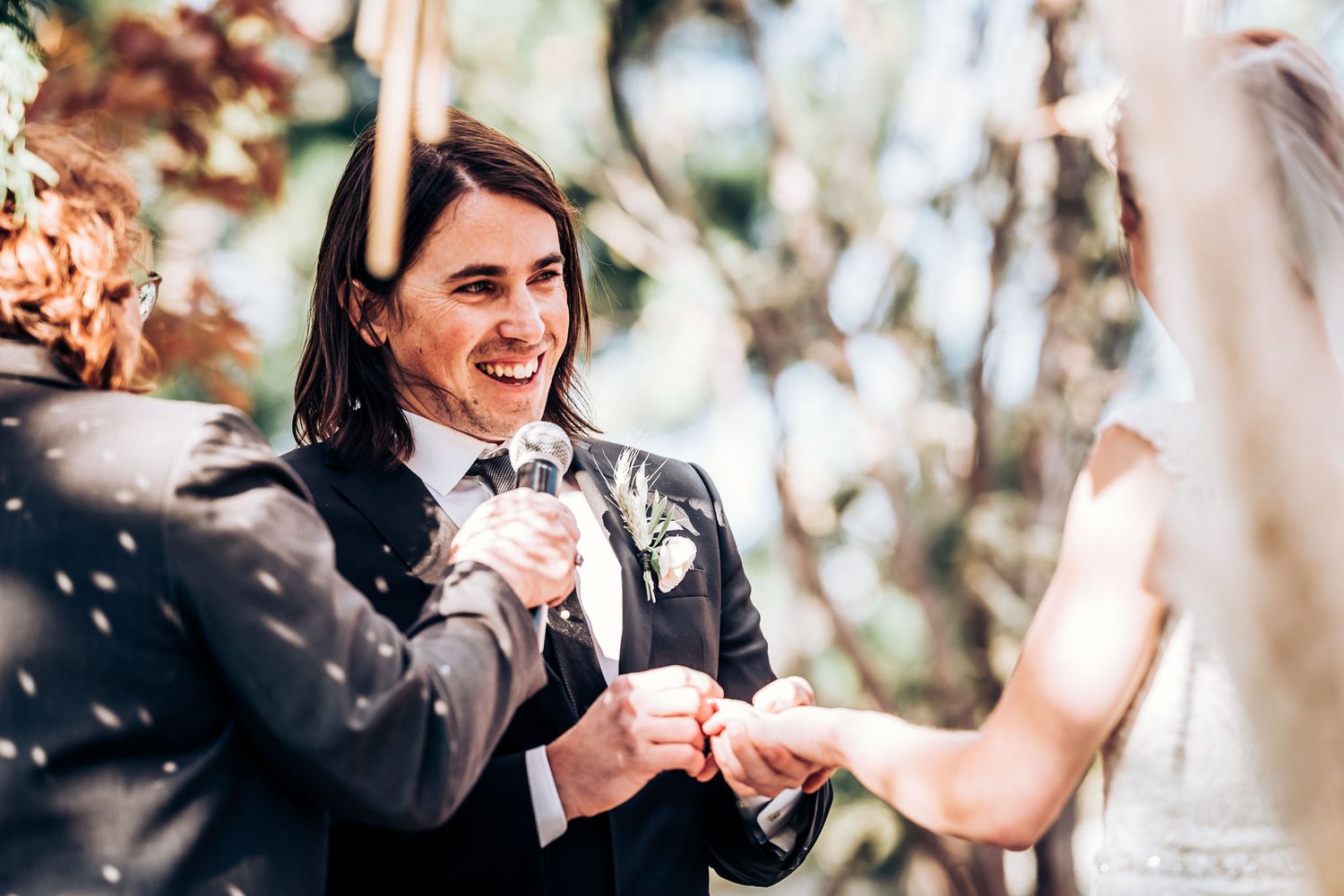Emotional moment during ring exchange at an outdoor garden wedding ceremony.