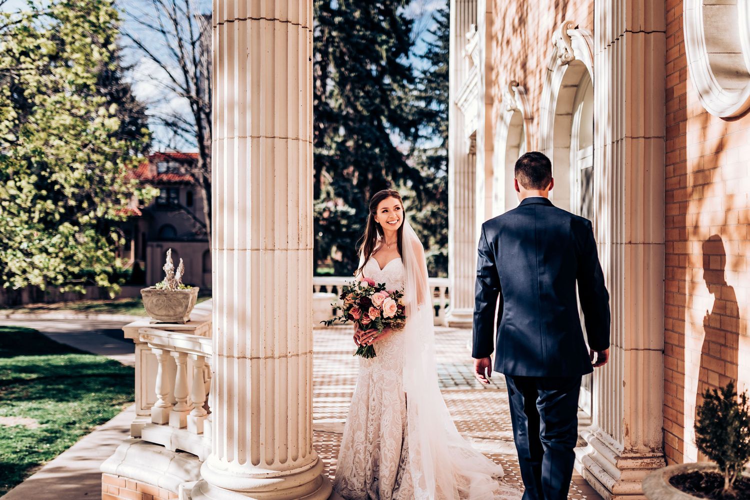 Couple explores elegant outdoor colonnade with grand pillars on their wedding day.