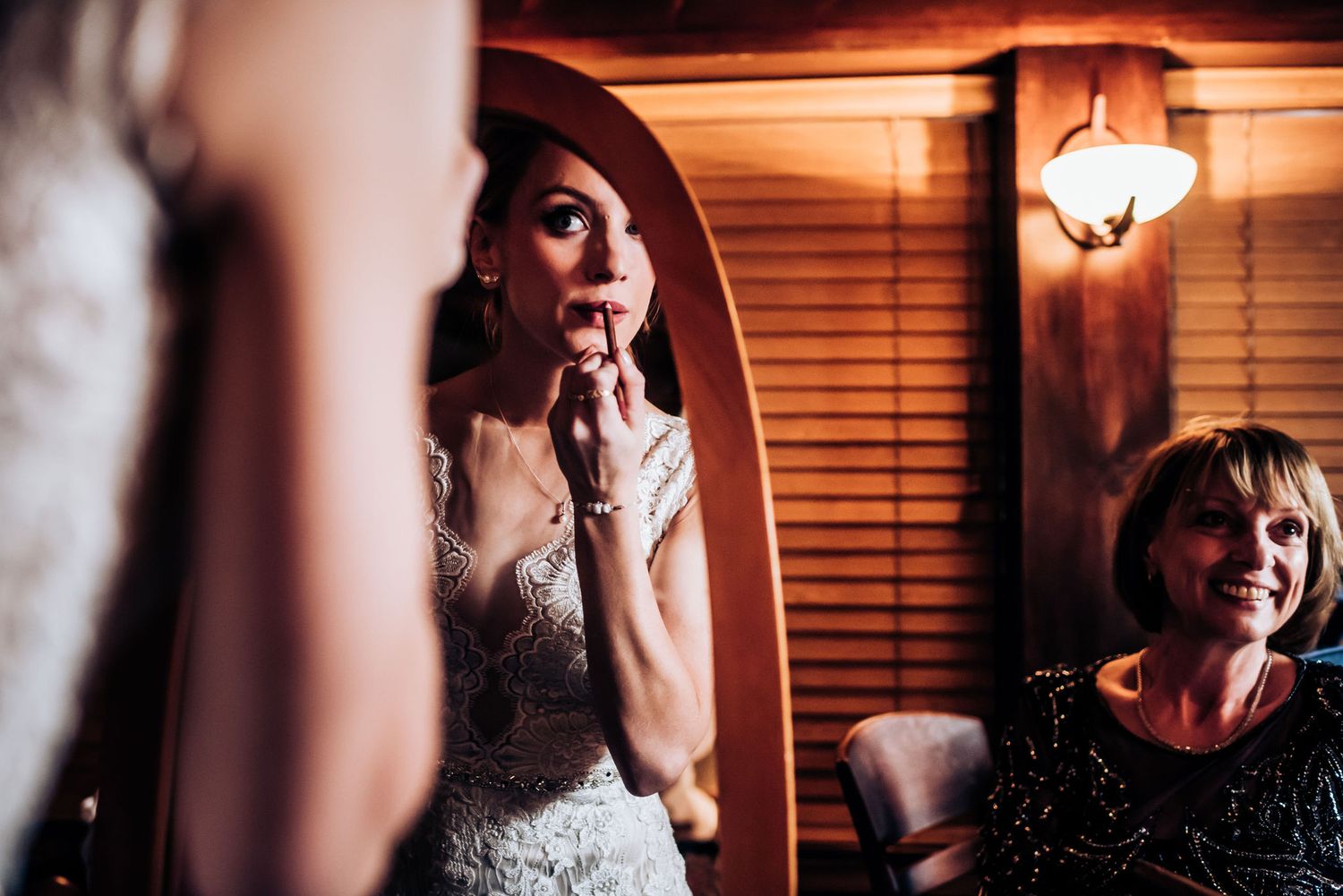 Close up of a wedding dress fitting in a warmly lit room with wooden blinds.
