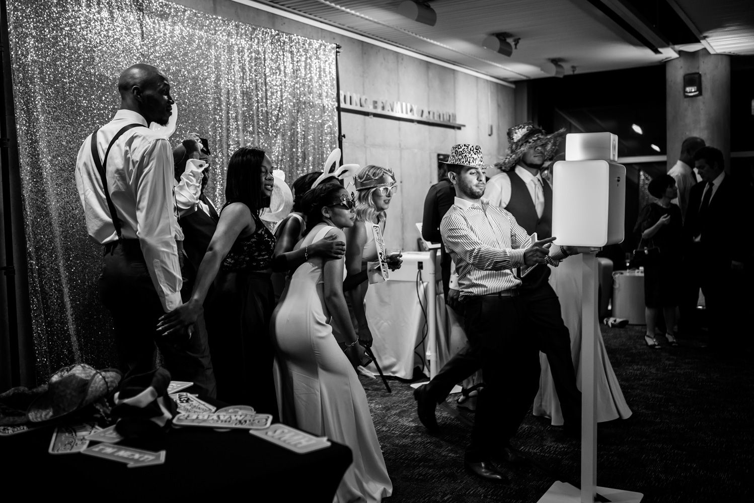 Wedding party members gather in front of a sparkly backdrop during reception festivities.