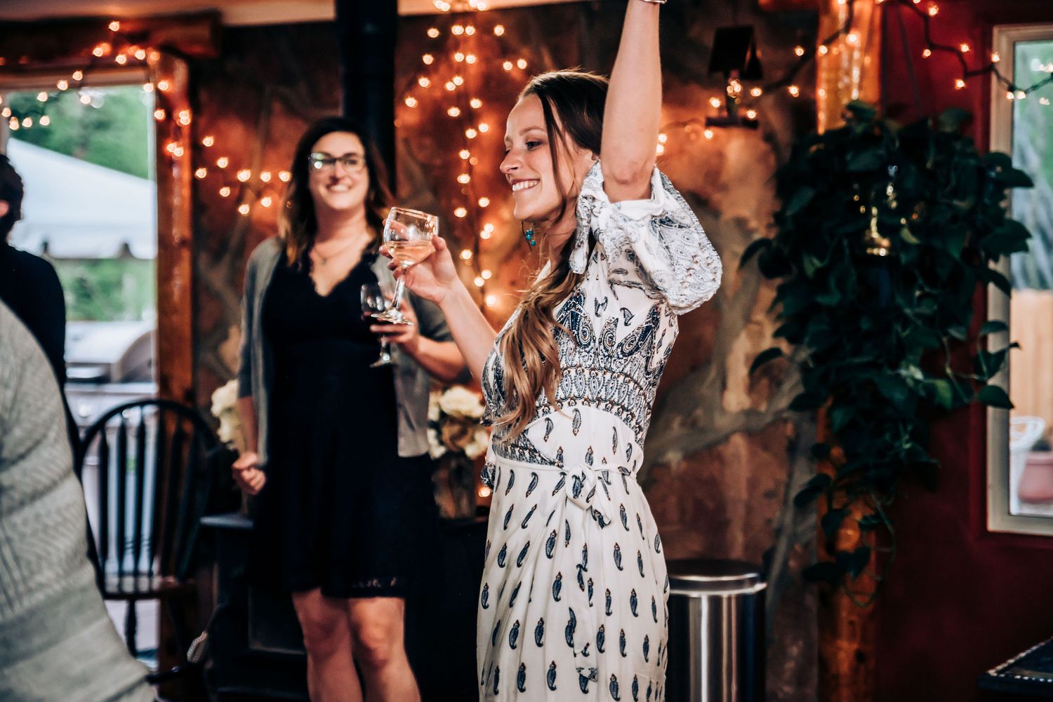 Guests dancing and celebrating at an indoor party with string lights and rustic decor.