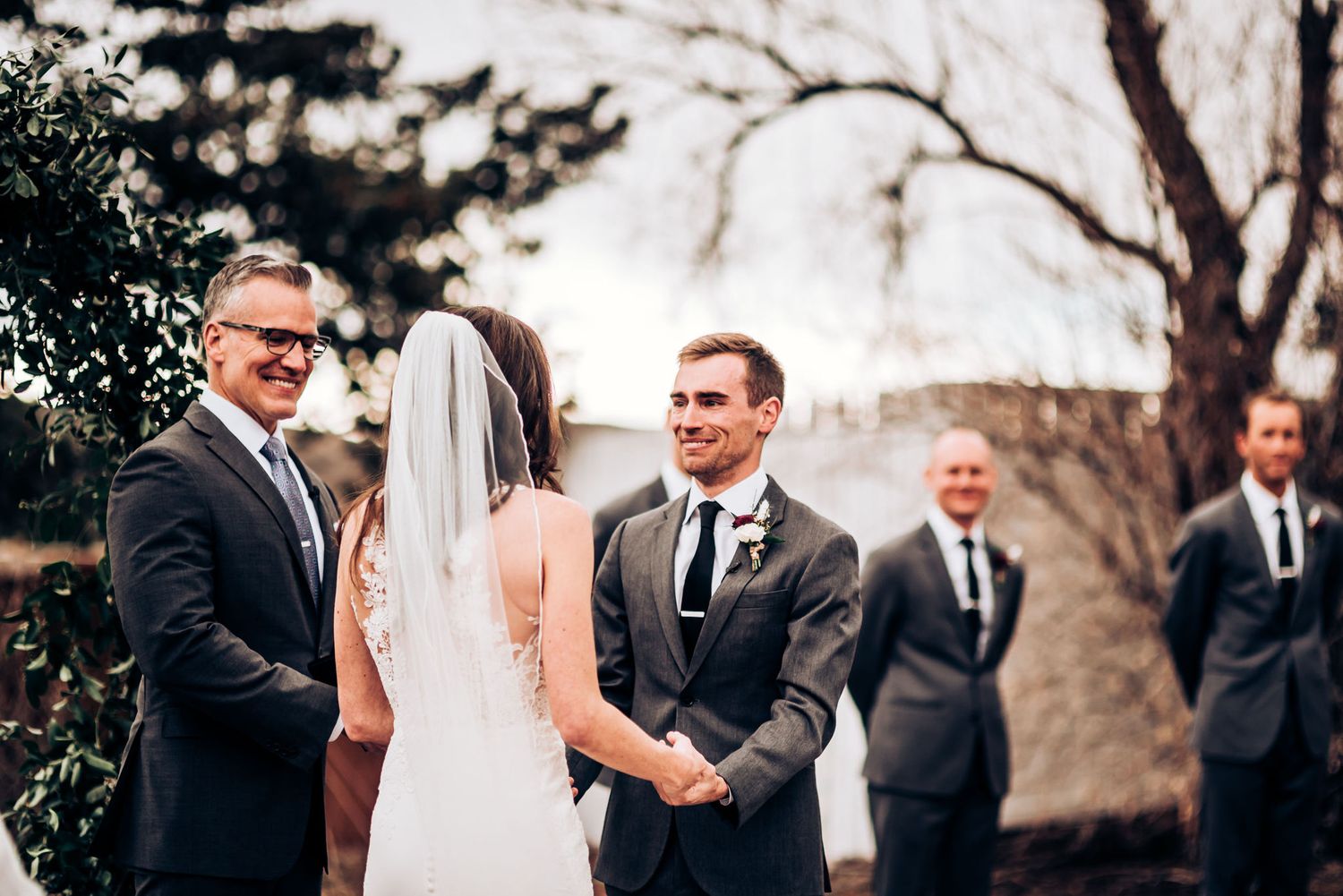 Outdoor wedding ceremony moment with formal attire against natural landscape.