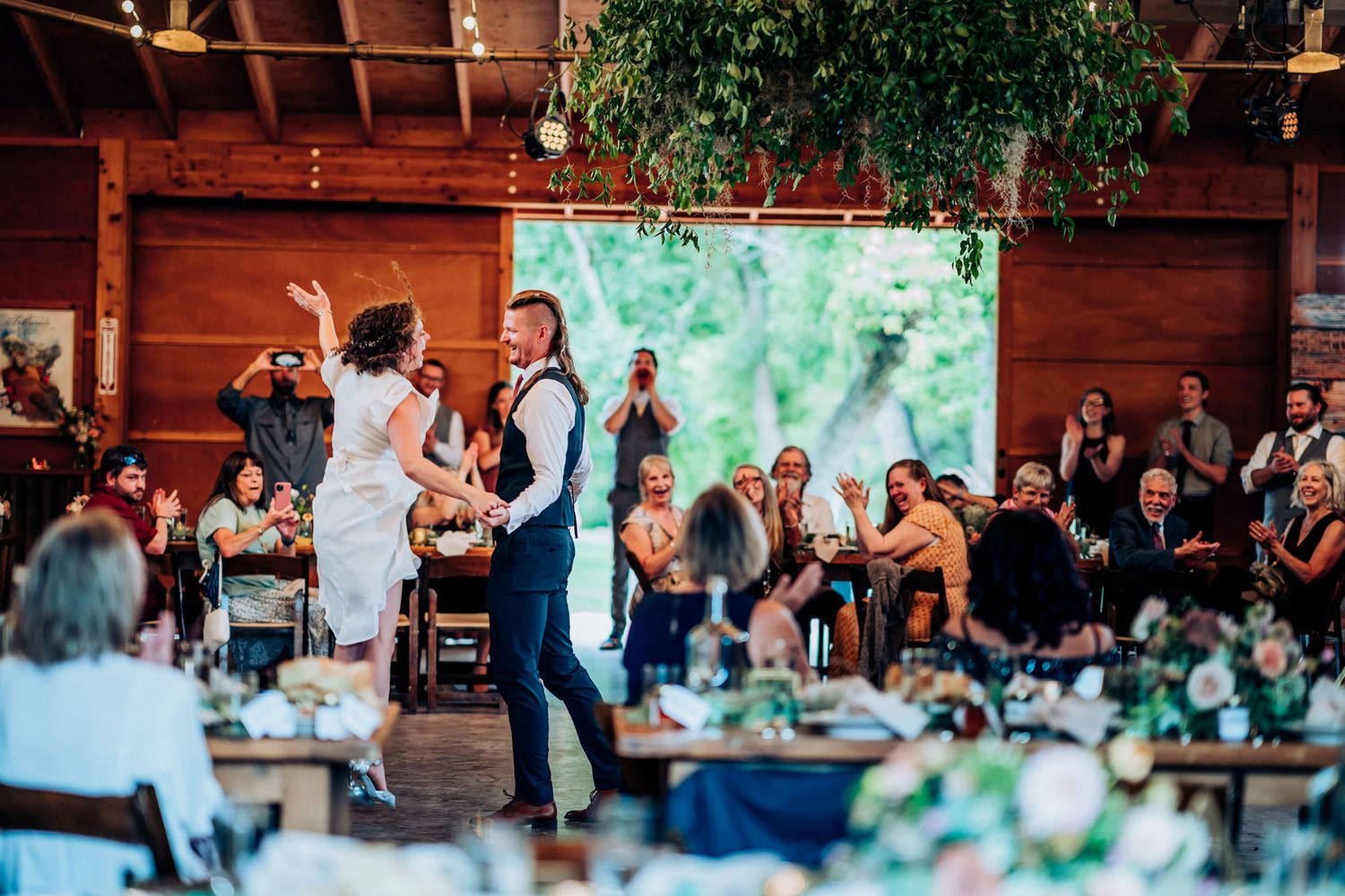 Dancers performing at a reception venue with elegant table settings and hanging greenery.
