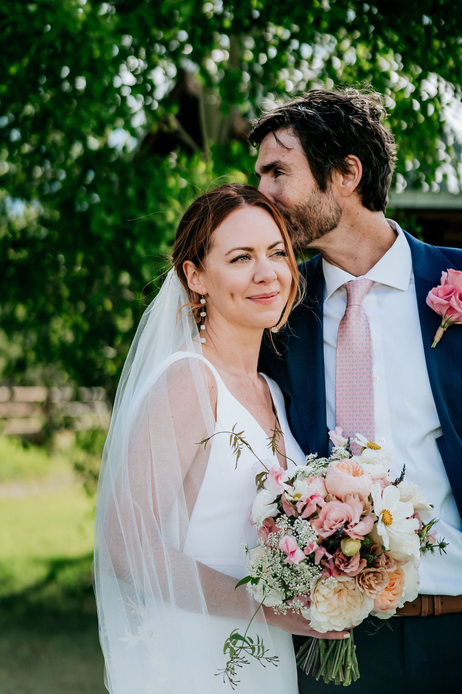 Intimate wedding portrait with soft natural lighting and pastel floral bouquet.