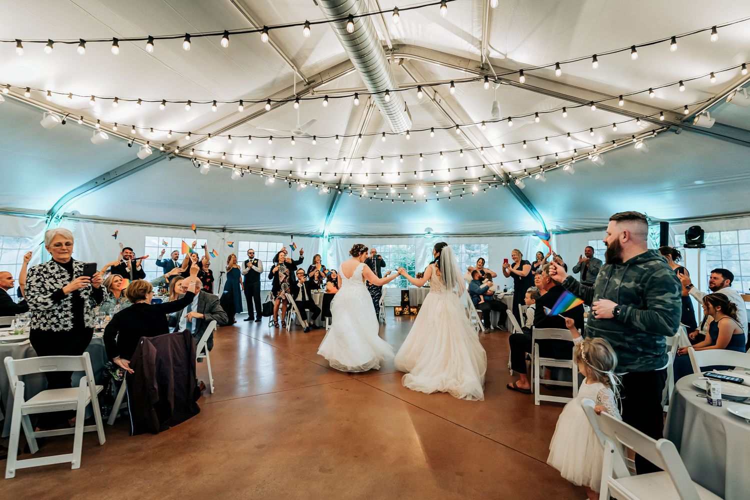 Reception venue decorated with string lights as wedding celebration unfolds with seated guests.