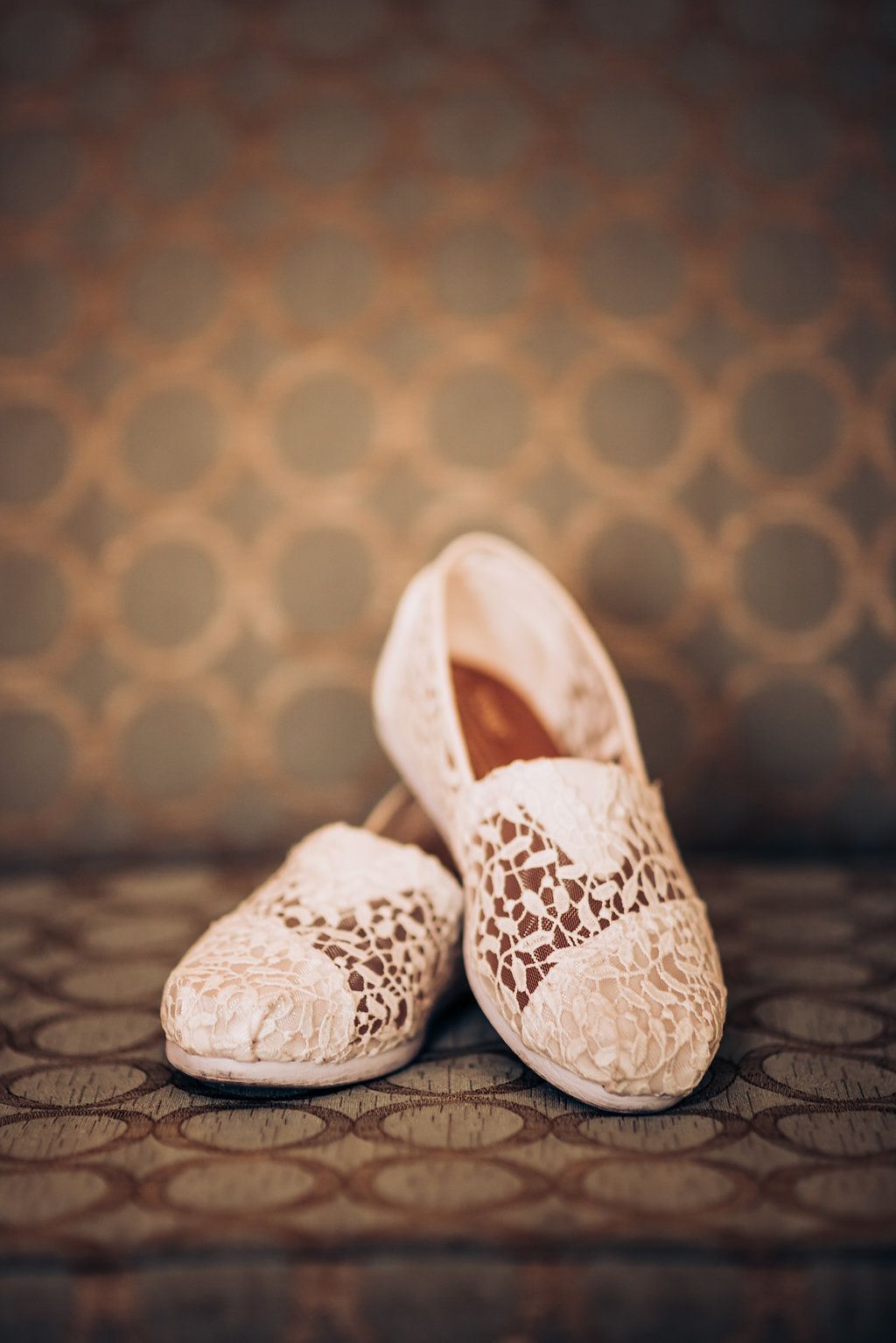 Cream colored lace flats photographed against a patterned background.