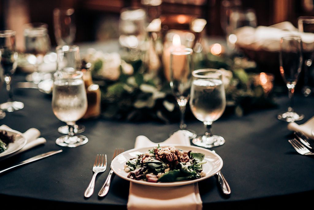 Elegant wedding reception table setting with plated meal and wine glasses.