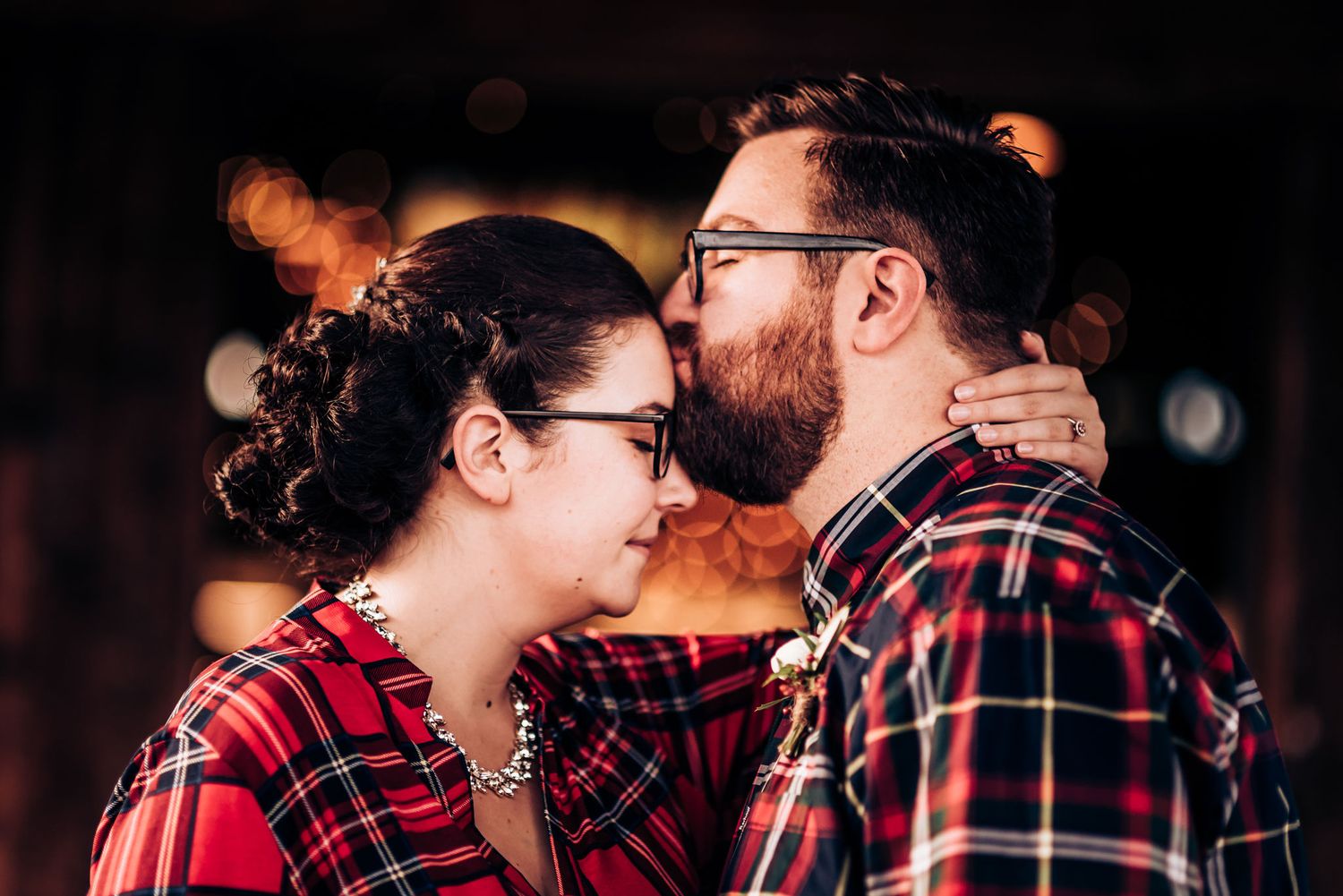 Romantic close-up of couple in matching plaid shirts sharing tender moment.