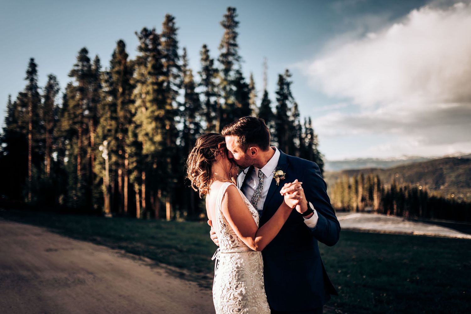 A romantic dance moment captured on a mountain road with pine trees in background.