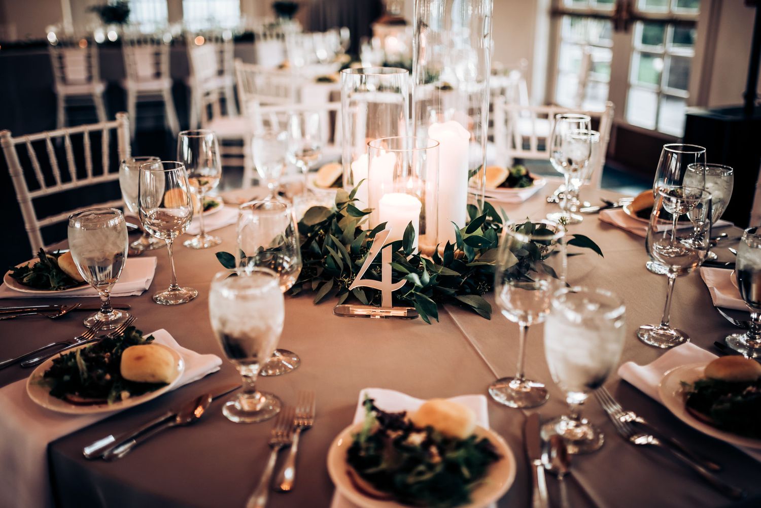 Elegant wedding table setting with candles, greenery and formal place settings.