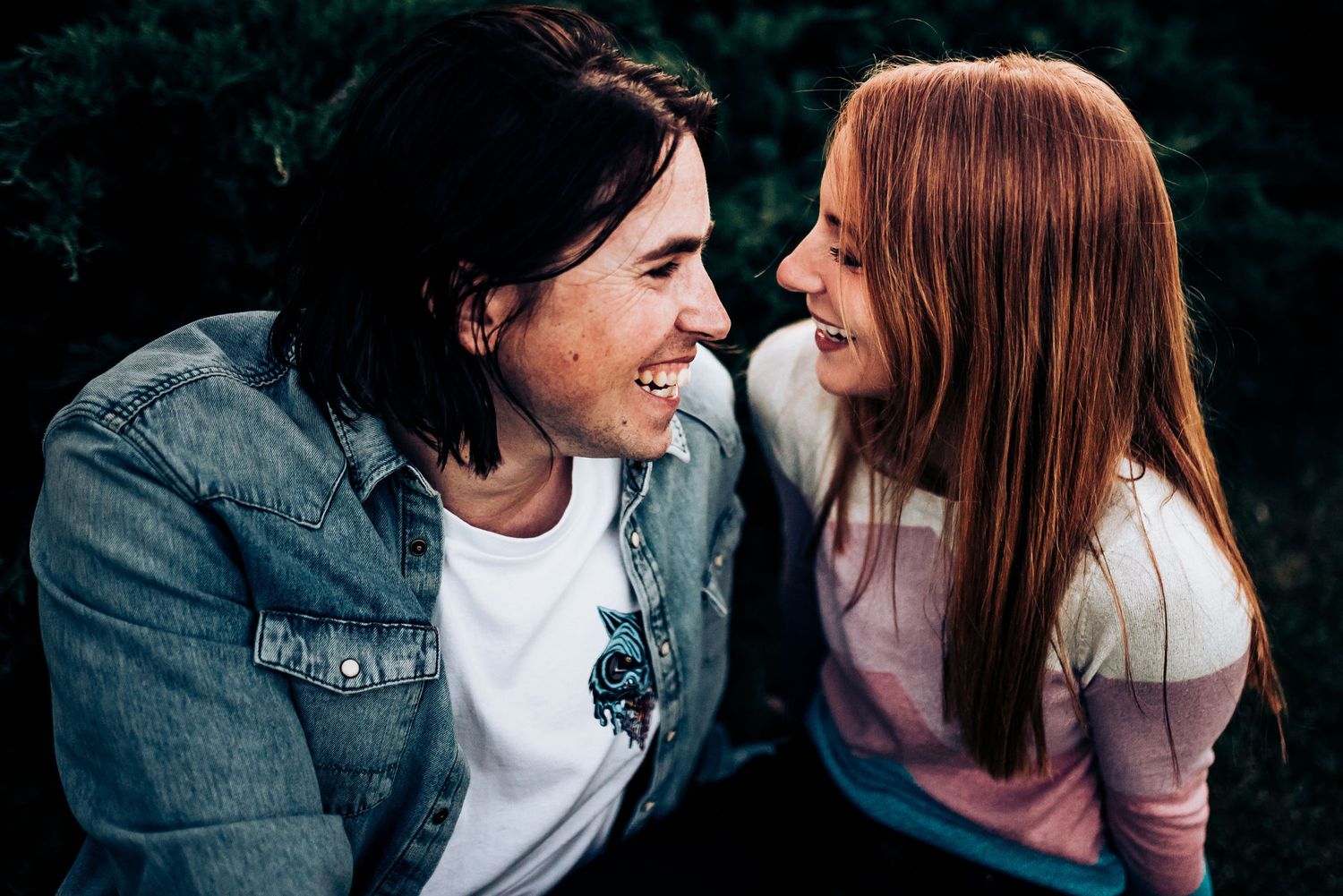 A couple shares an intimate moment of laughter while wearing casual attire.