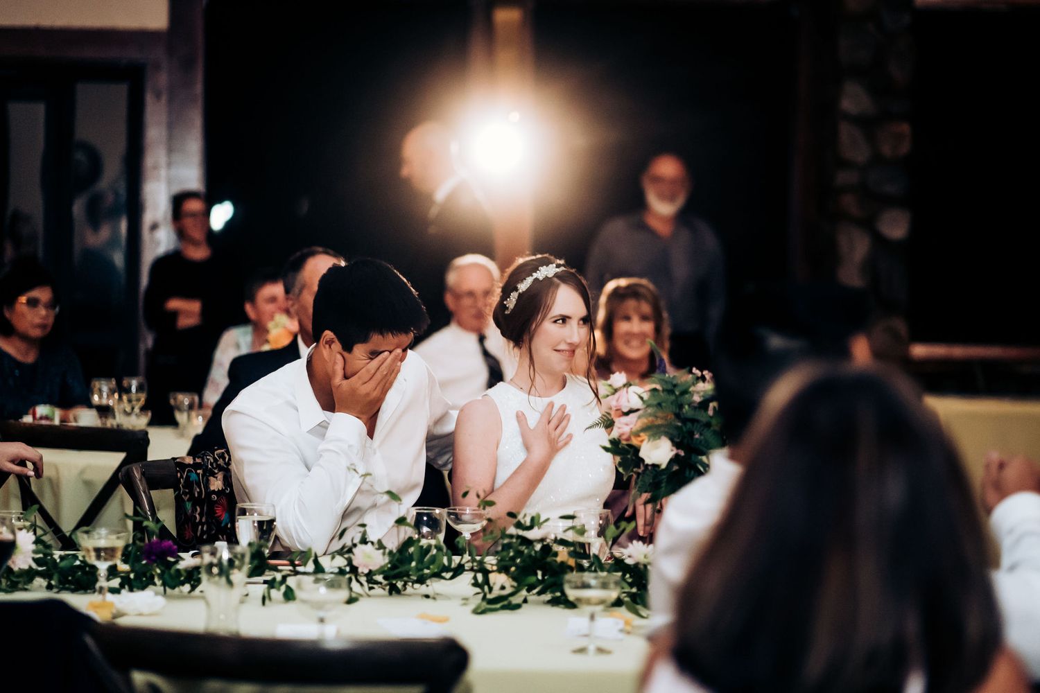 Wedding party seated at decorated tables during reception dinner.