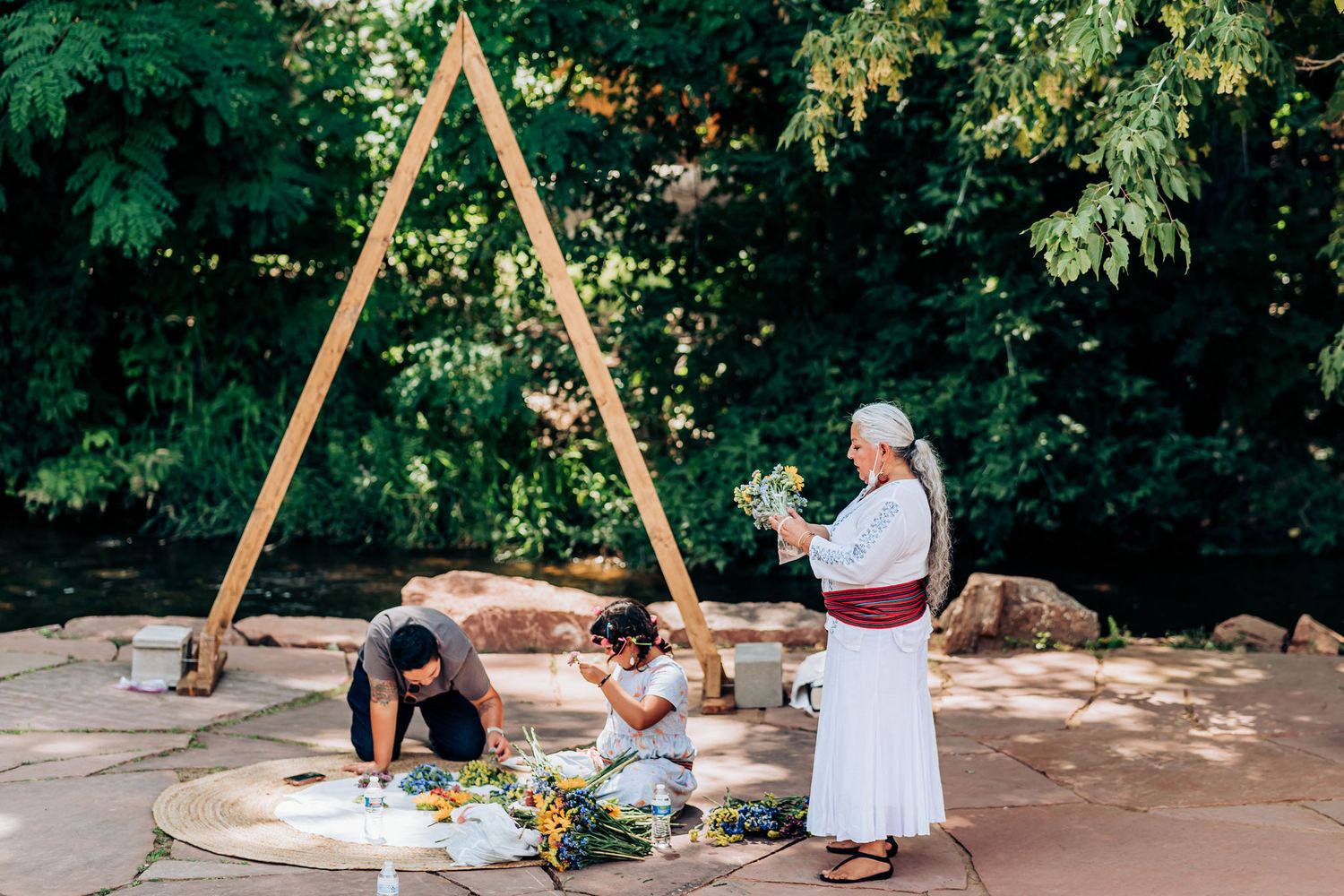 Outdoor ceremony preparation under wooden triangular arch structure.