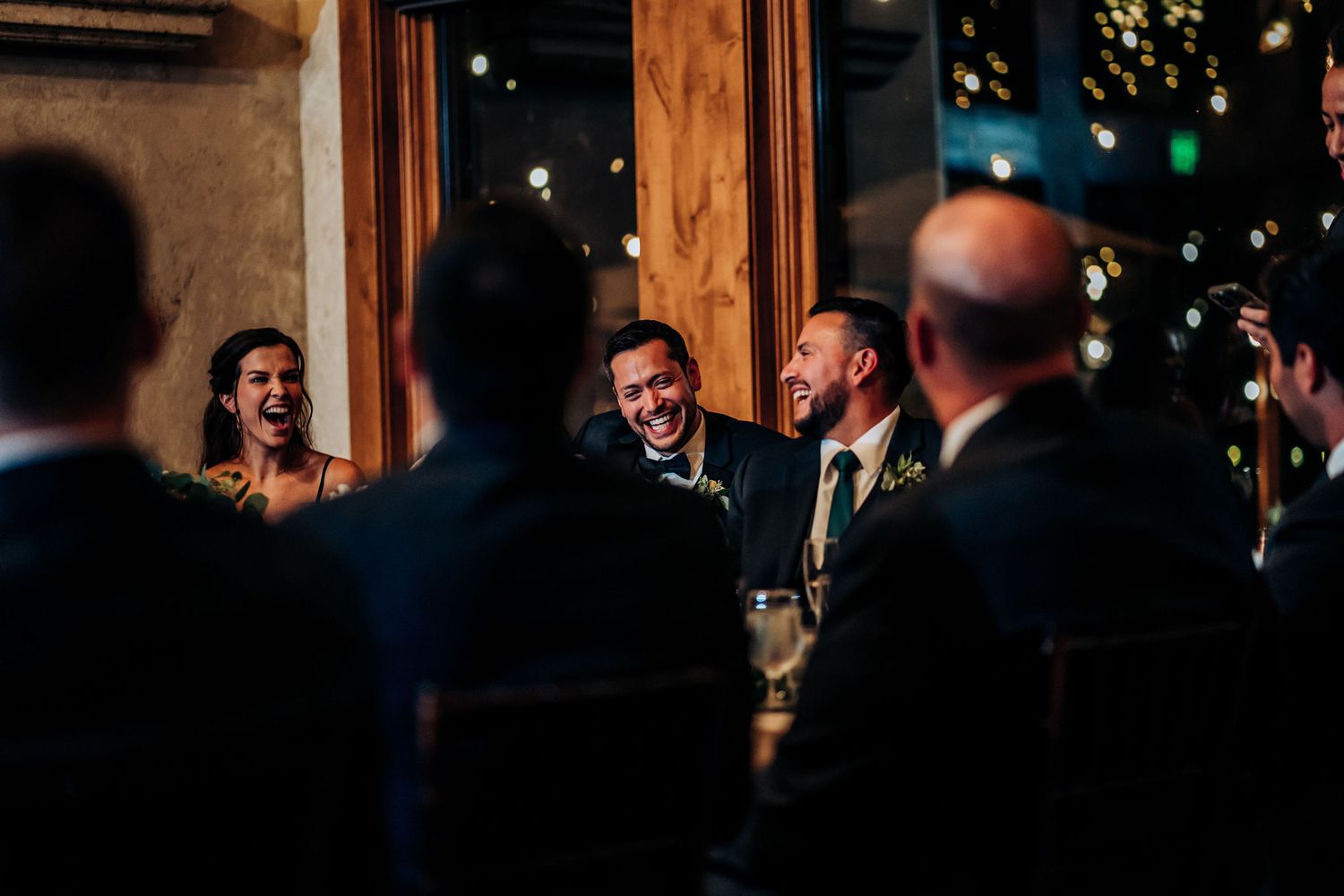 Wedding guests share laughter during evening reception speeches and toasts.