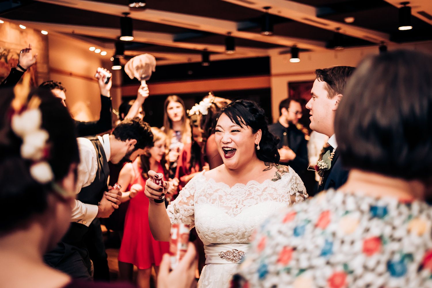 Joyful celebration with guests dancing and cheering at an indoor wedding reception.