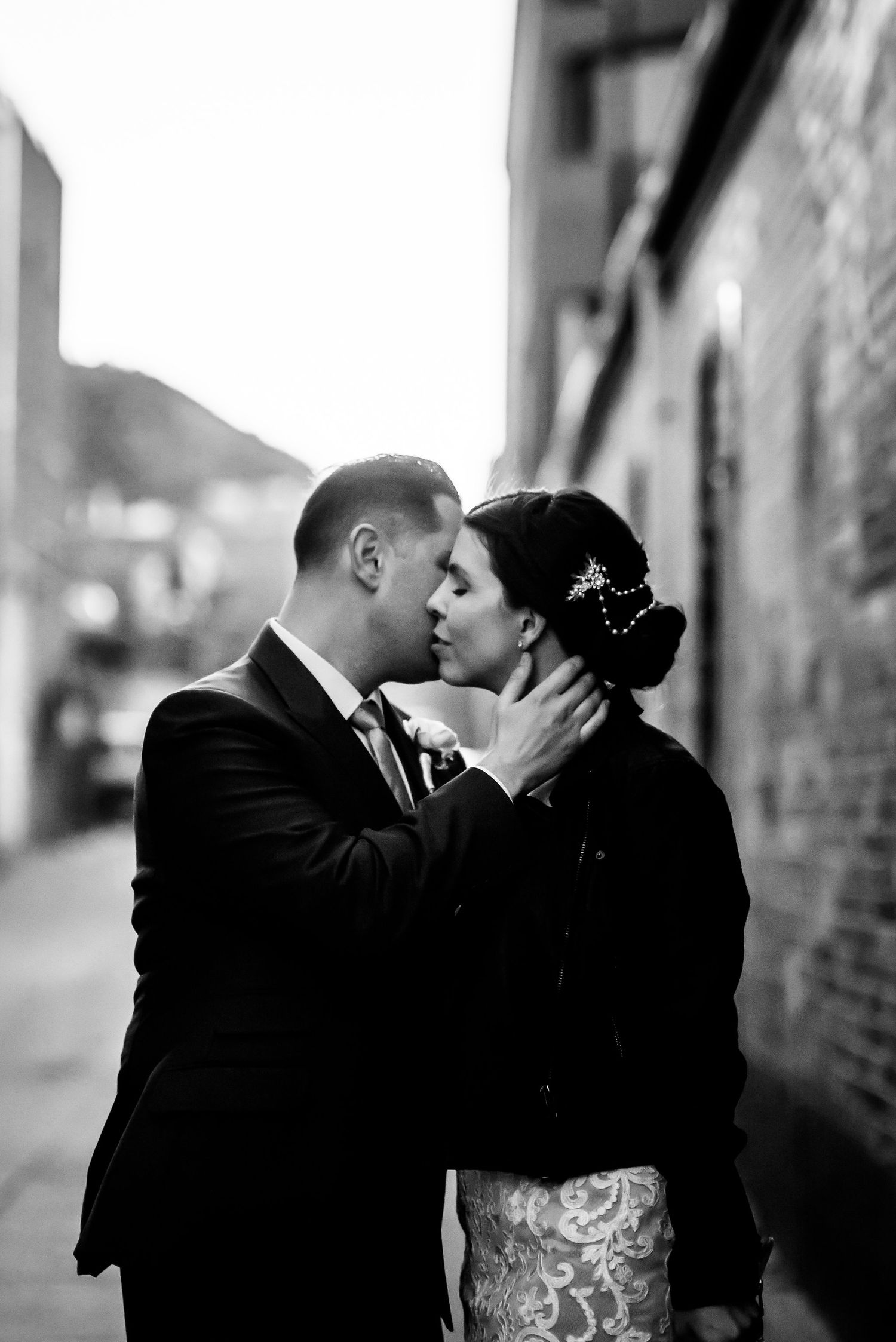 Black and white intimate wedding portrait in urban alleyway.