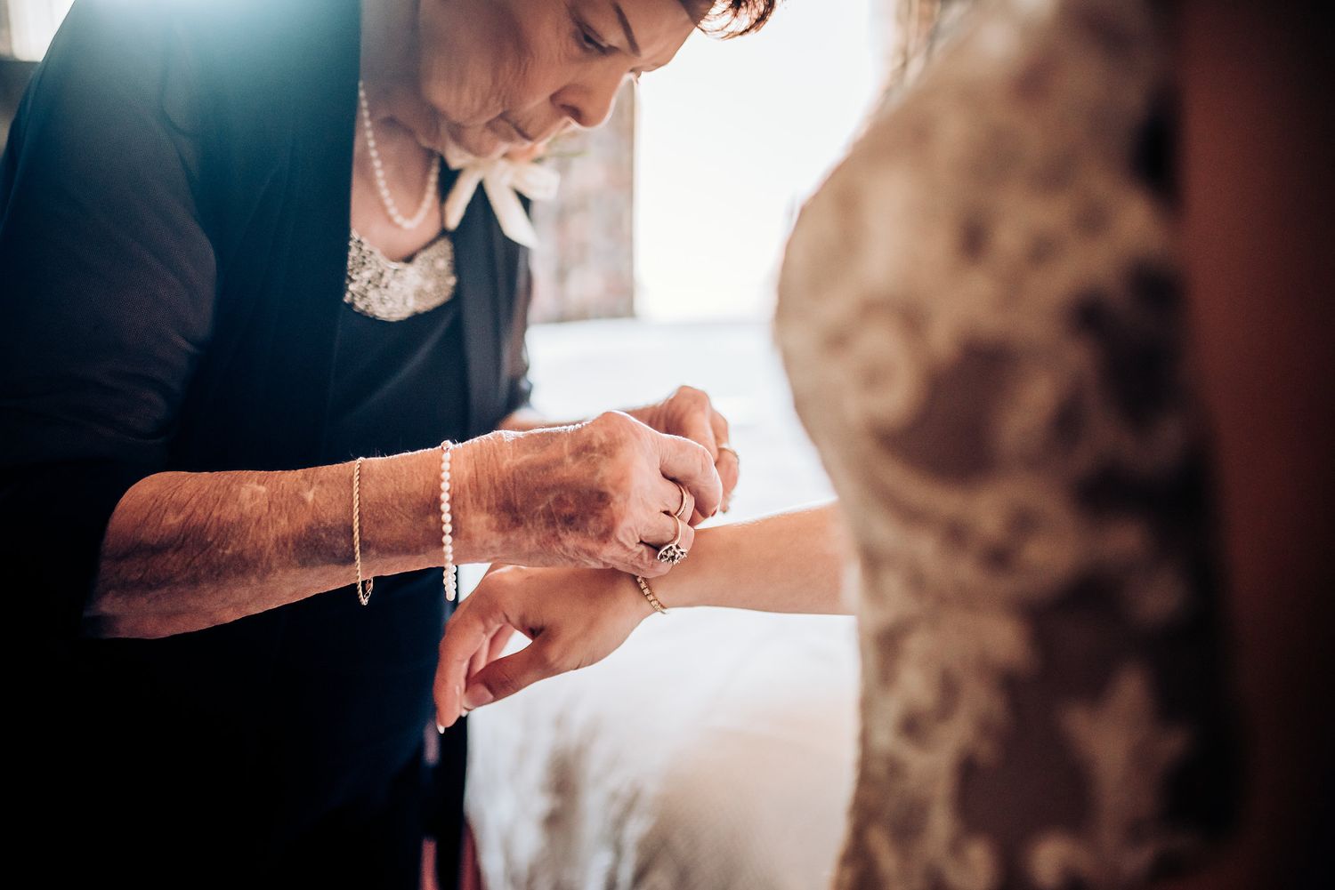 Close-up shot of hands adjusting jewelry in soft window light.