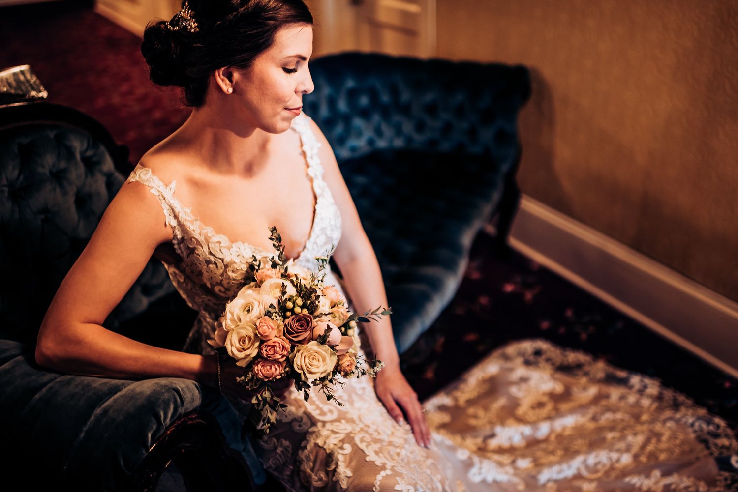 Elegant wedding photography on a blue velvet sofa with soft lighting.